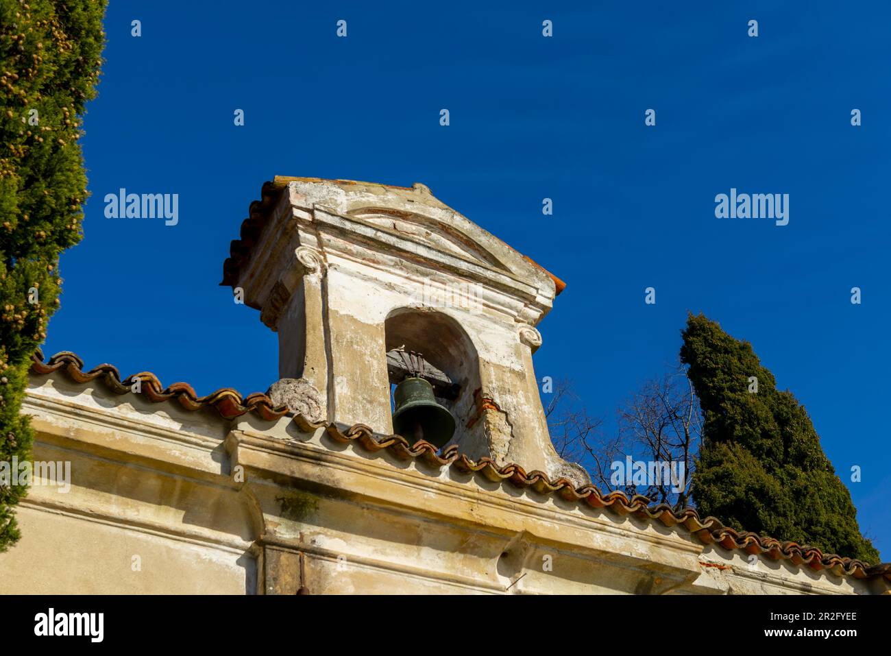 Kirche mit Glocke und einem Baum mit klarem blauen Himmel im Park San Michele in Castagnola in Lugano, Tessin in der Schweiz Stockfoto