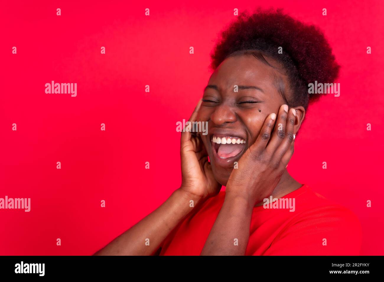 Junge afroamerikanische Frau isoliert auf rotem Hintergrund, lächelnd und lachend, Studioaufnahme Stockfoto