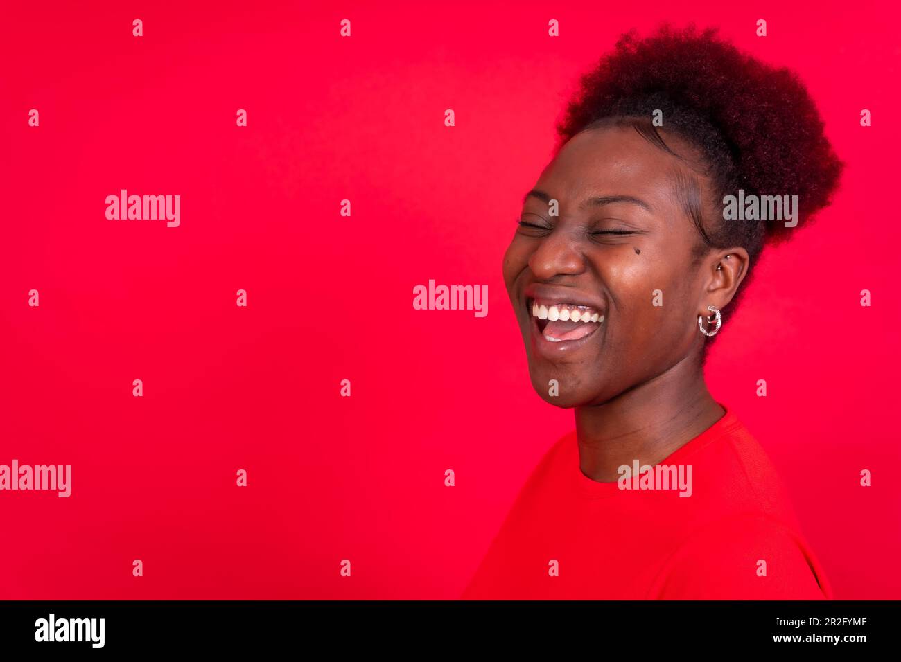 Junge afroamerikanische Frau isoliert auf rotem Hintergrund, lächelnd und lachend, Studioaufnahme Stockfoto