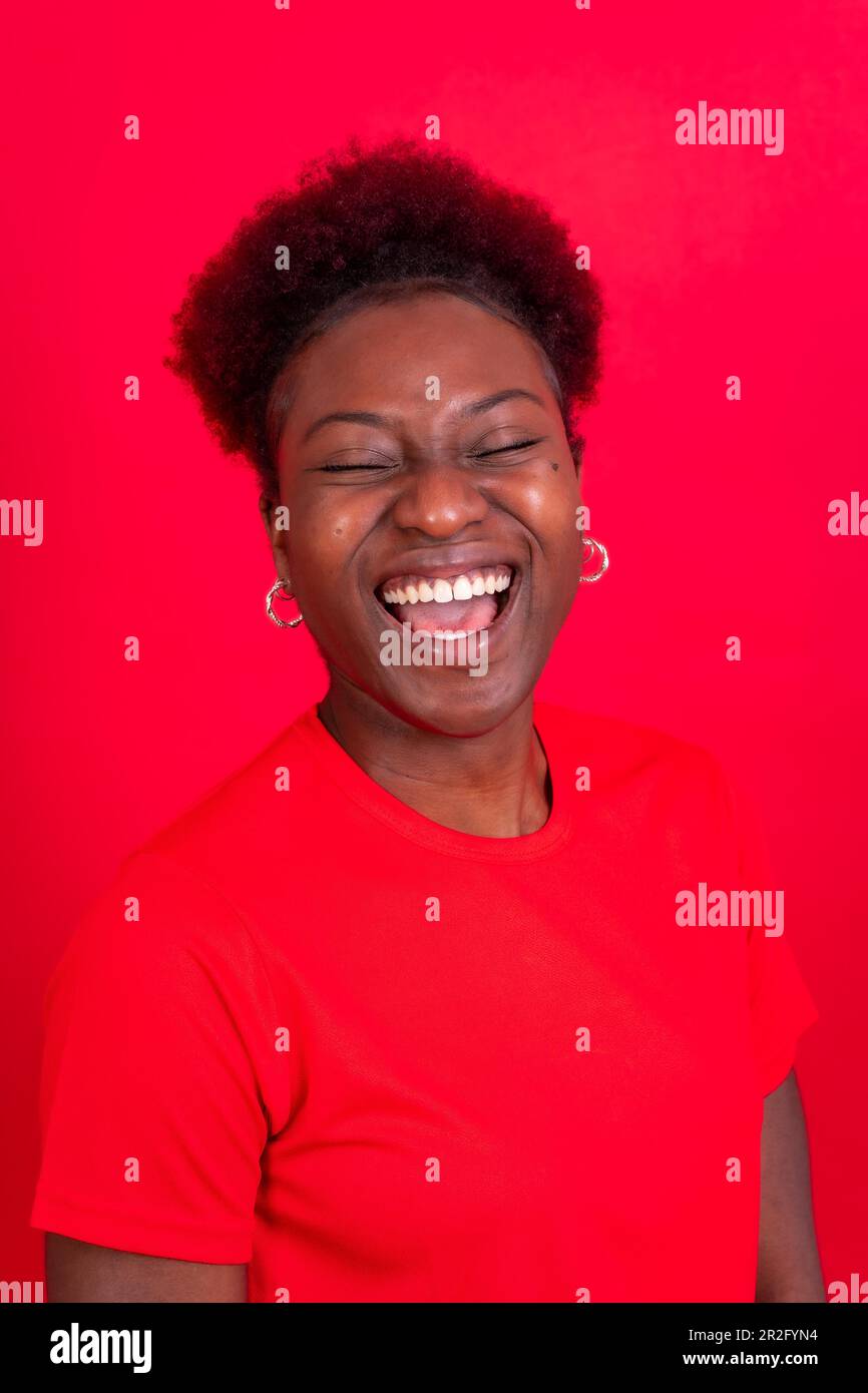 Junge afroamerikanische Frau isoliert auf rotem Hintergrund, lächelnd und lachend, Studioaufnahme Stockfoto