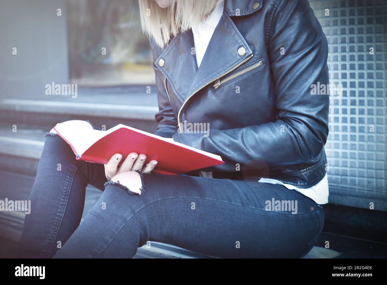 Junge Hipsterin, die in einem roten Tagebuch nachsieht, aus der Nähe Stockfoto