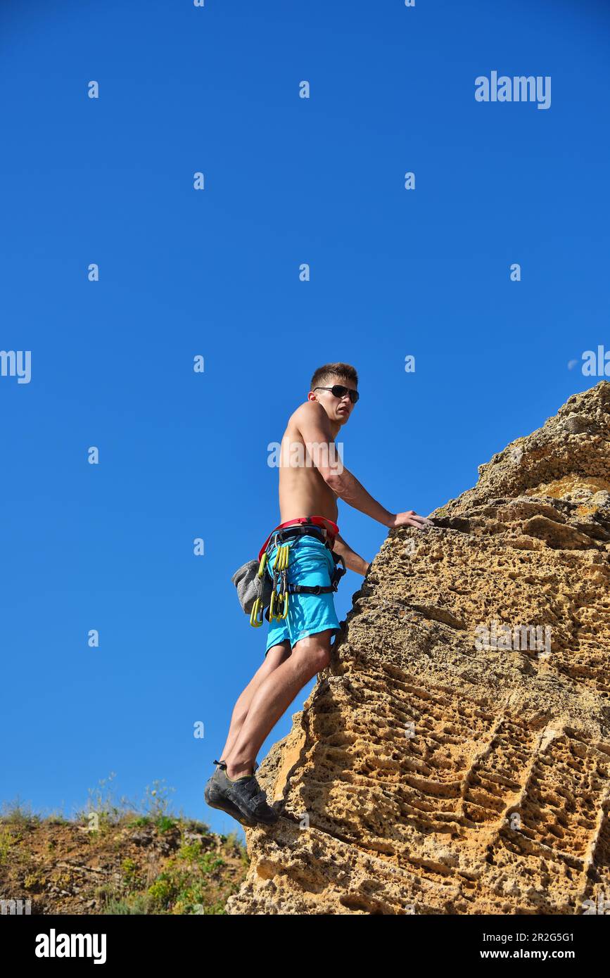 Rückansicht eines jungen männlichen Kletterers beim Klettern mit Karbinen Stockfoto