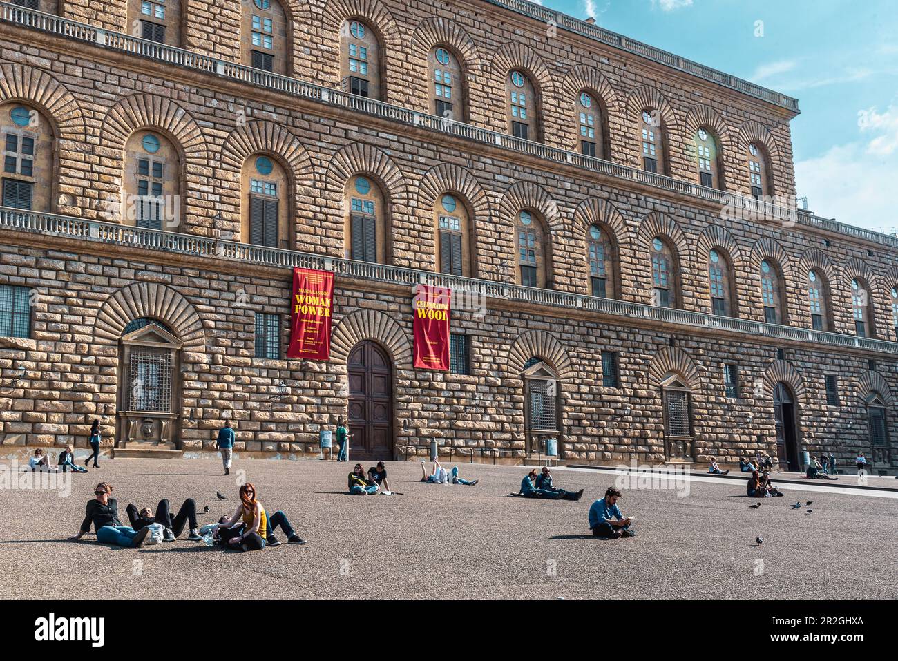 Menschen, die vor dem Palazzo Pitti Renaissance Palast im Stadtteil Oltrarno von Florenz, Florenz, Toskana, Italien, Europa liegen oder sitzen Stockfoto