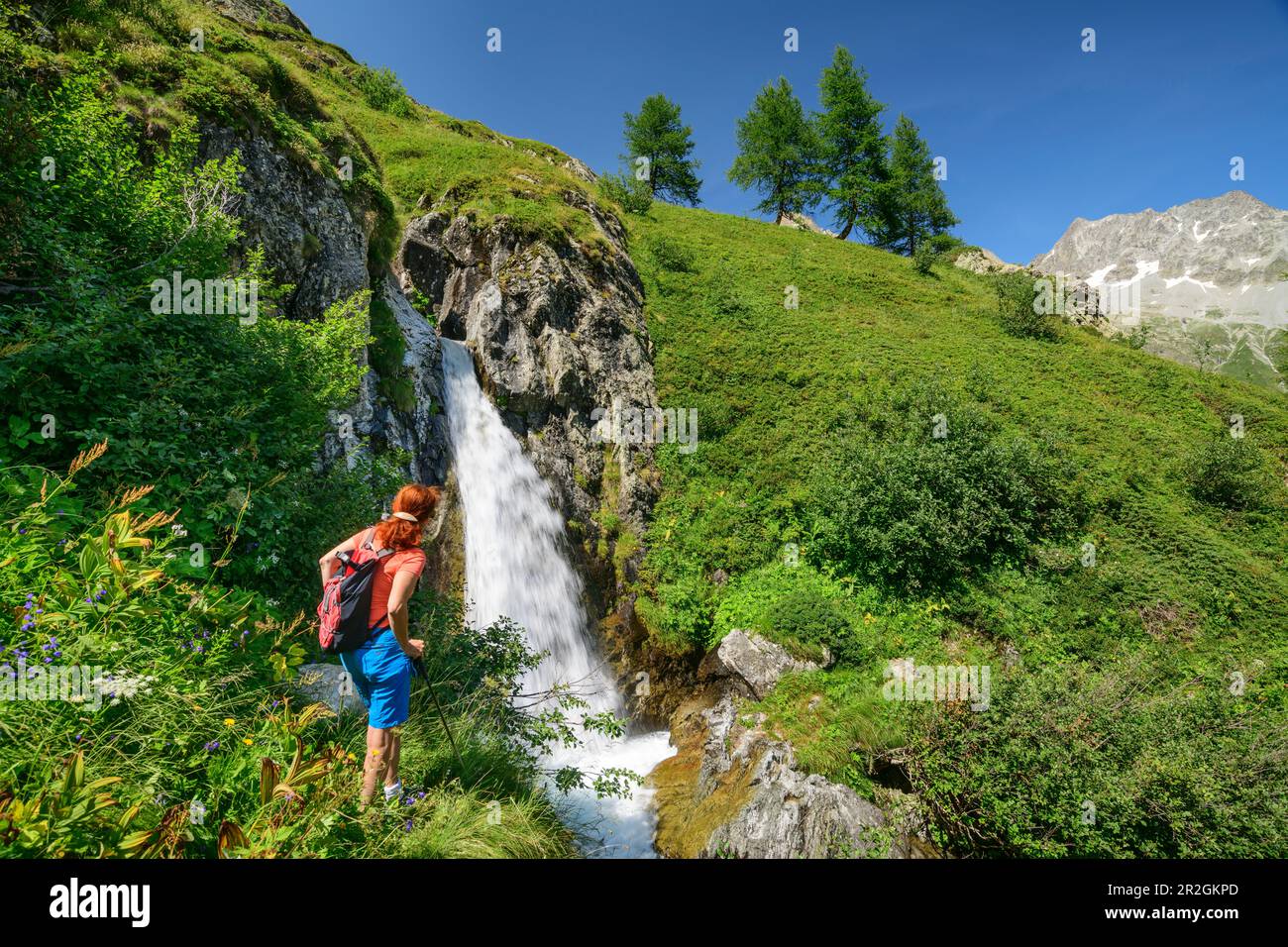 Frau wandert mit Blick auf den Wasserfall, am Lac du Lauzon, Valgaudemar, Ecrins National Park, Dauphine, Provence-Hautes Alpes, Frankreich Stockfoto