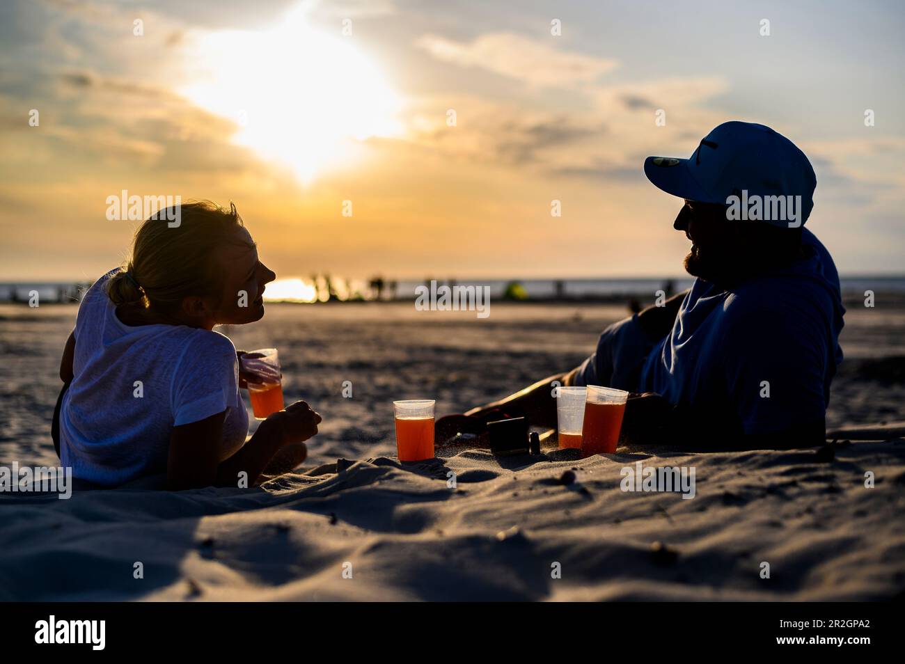 Mann und Frau genießen den Sonnenuntergang mit einem Drink, Ording District, St. Peter Ording, Nordfriesland, Nordseeküste, Schleswig Holstein, Deutschland, Europa Stockfoto