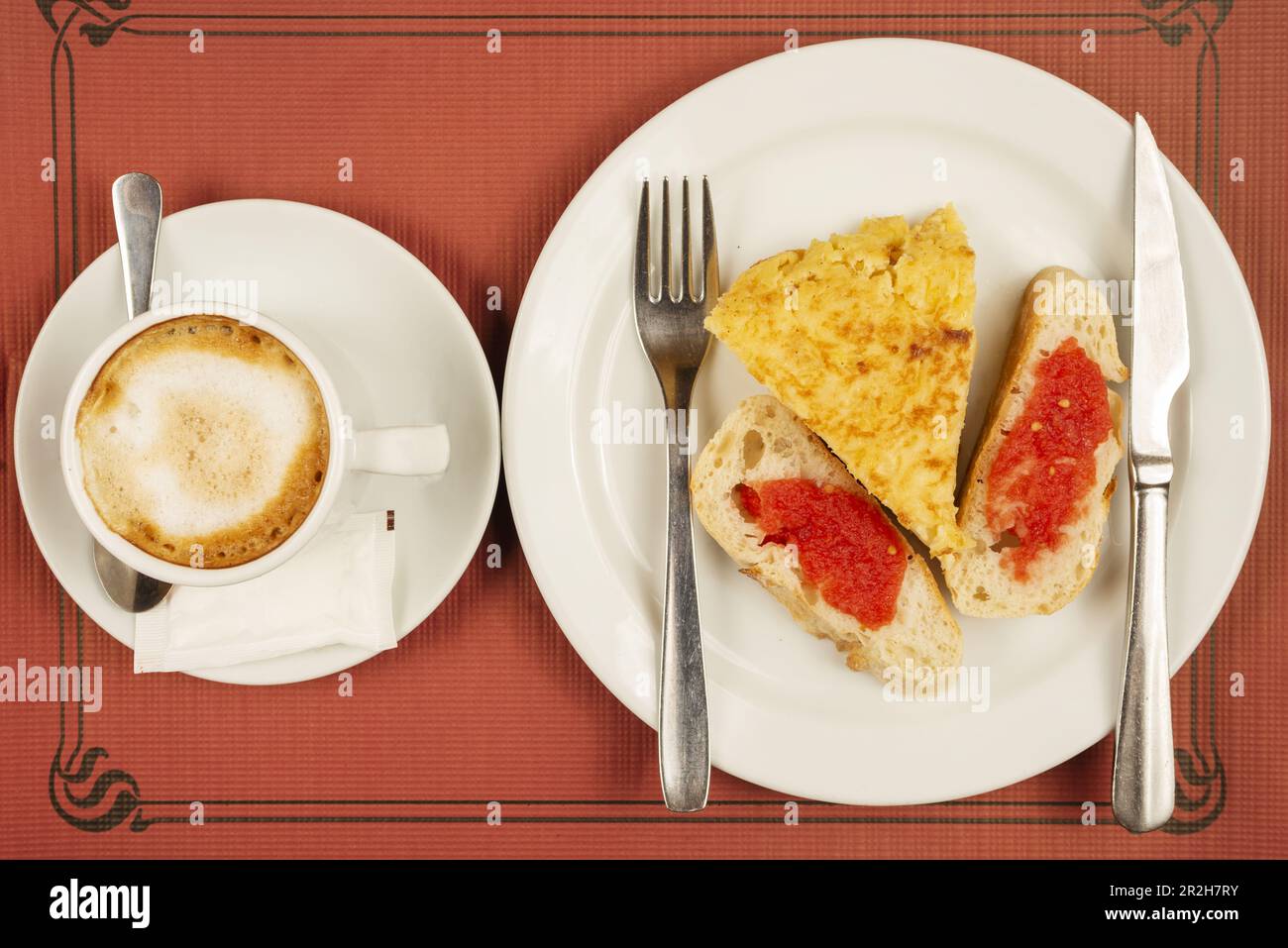 Ein typisch spanisches Frühstück mit Tortilla-Spieß mit Scheiben Brot mit Tomaten und Kaffee mit Milch in einer Tasse Stockfoto