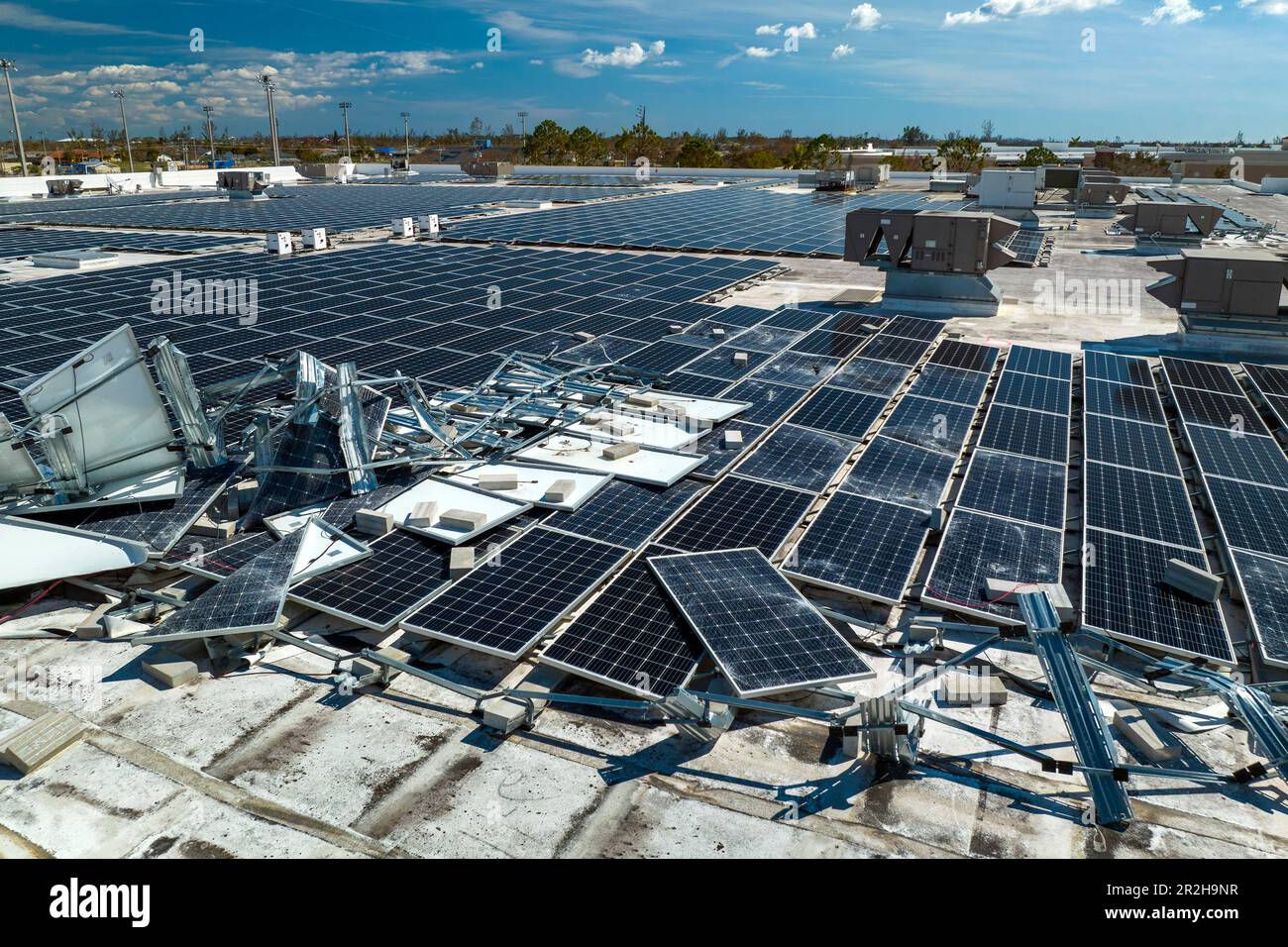 Draufsicht der durch den Hurrikan Ian zerstörten Photovoltaik-Solarpaneele, die auf dem Dach des Industriebaues zur Erzeugung von ökologischem Strom montiert sind Stockfoto