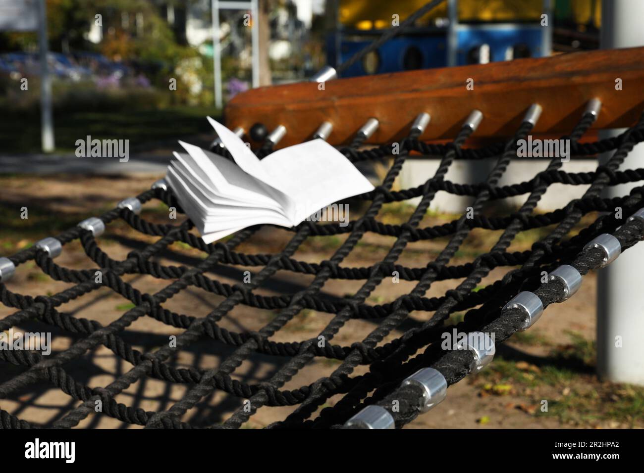 Komfortable NetzHängematte mit offenem Buch im Freien an sonnigen Tagen Stockfoto