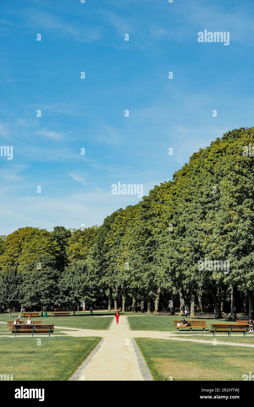 Frau in Rot, die durch den Park du Cinquantenaire in Brüssel, Belgien, spaziert Stockfoto