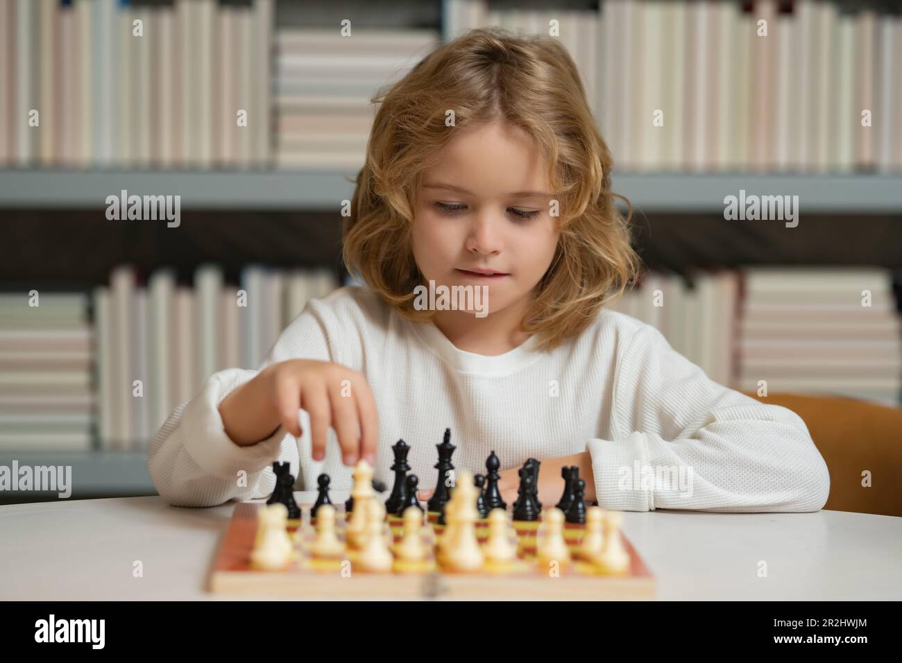 Schachspiel für Kinder. Ein Schuljunge, der im Klassenzimmer Schach spielt. Kinder Frühentwicklung. Ein Junge, der zu Hause Schach spielt. Porträt aus der Nähe, komisches Gesicht. Stockfoto