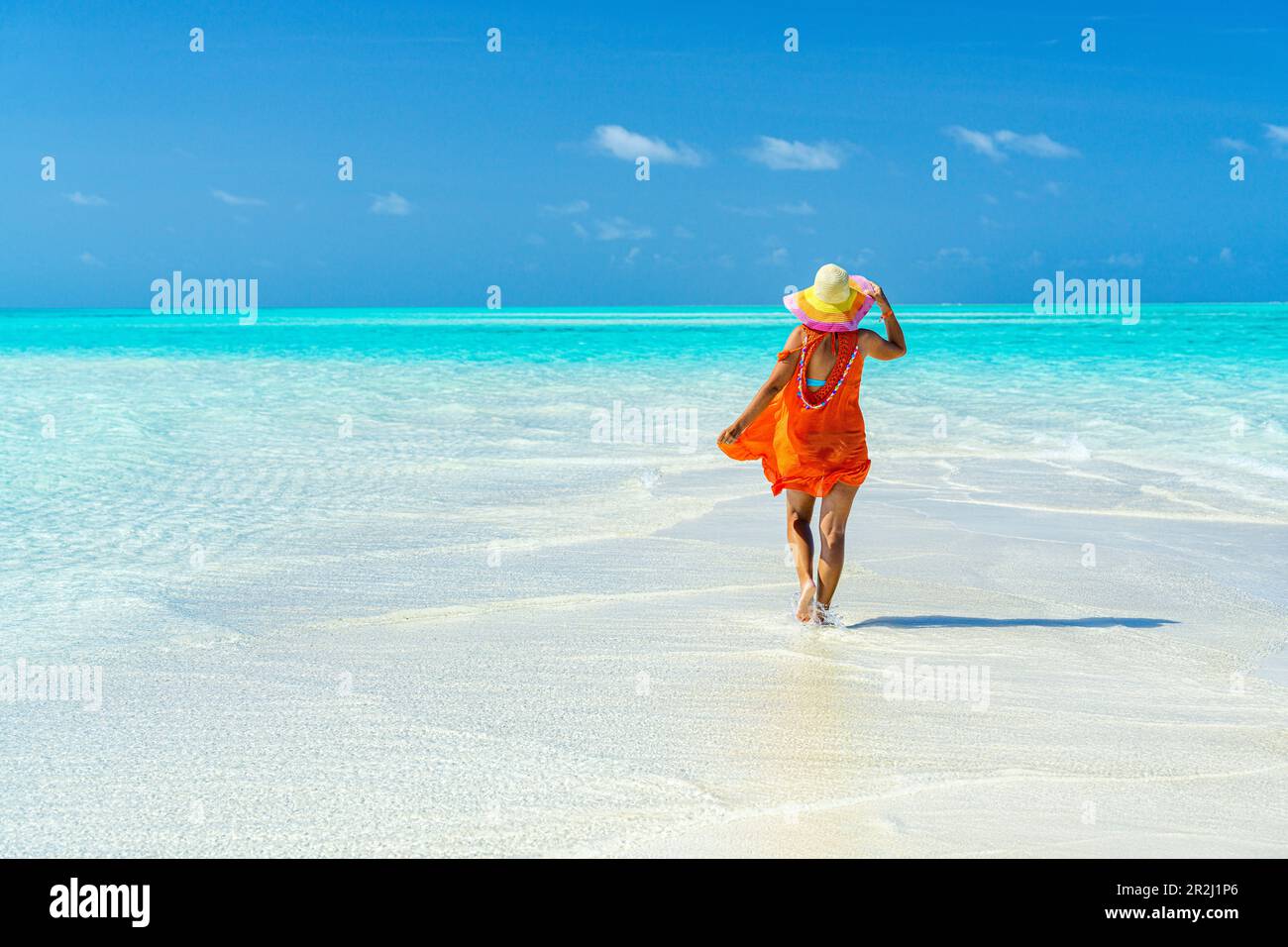 Frau mit Hut, die zum kristallklaren Meer geht, Sansibar, Tansania, Ostafrika, Afrika Stockfoto