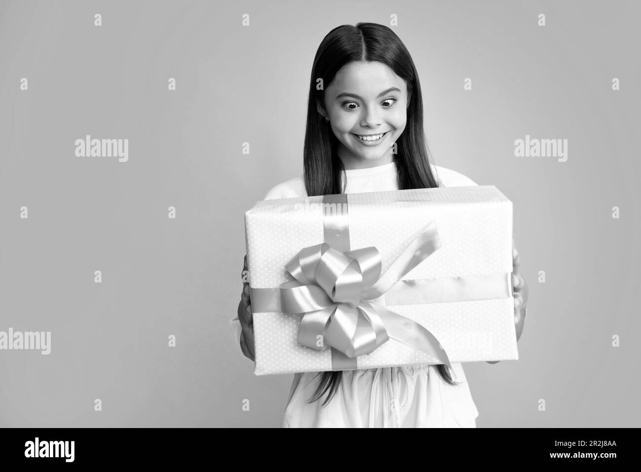 Teenager mit Geschenkbox. Ein Mädchen, das Geburtstagsgeschenk macht. Geschenk-, Begrüßungs- und Geschenkkonzept. Überraschtes Gesicht, überraschende Emotionen von Teenager gi Stockfoto
