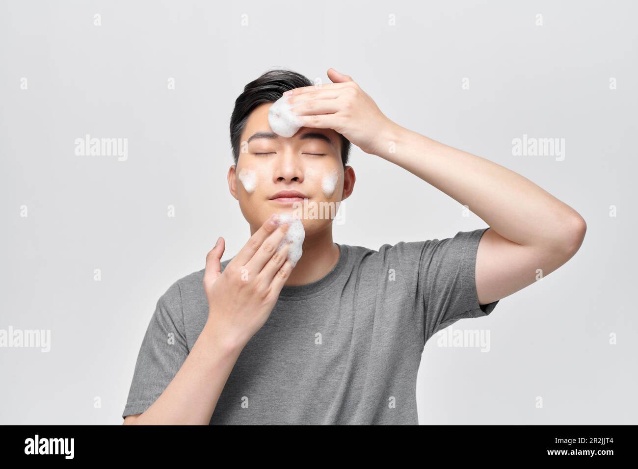 Junger Mann wäscht sich das Gesicht mit Reinigungsschaum, Männer-Hautpflegekonzept Stockfoto