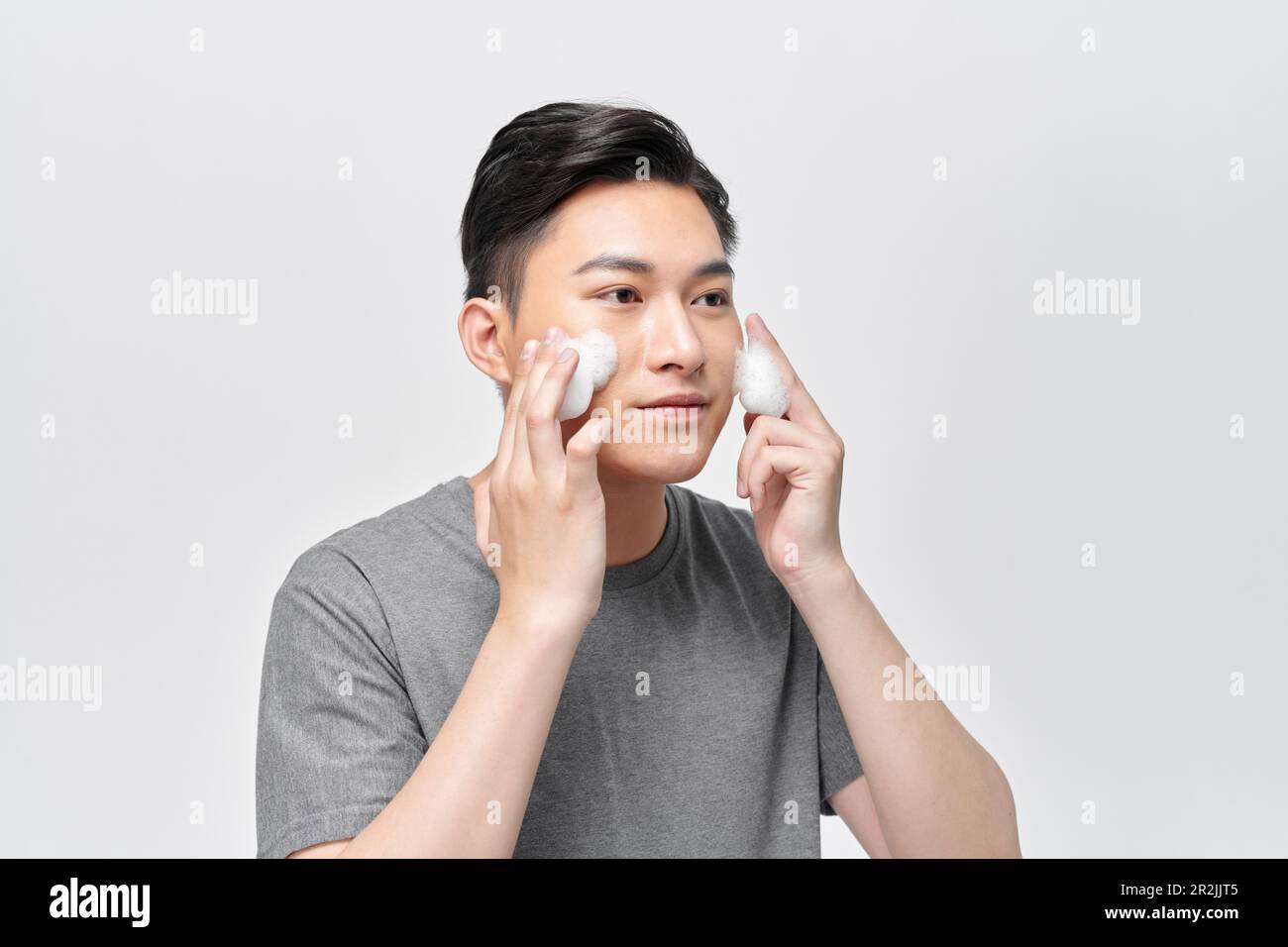 Ein Mann wäscht sich das Gesicht mit Schaumseife Stockfoto