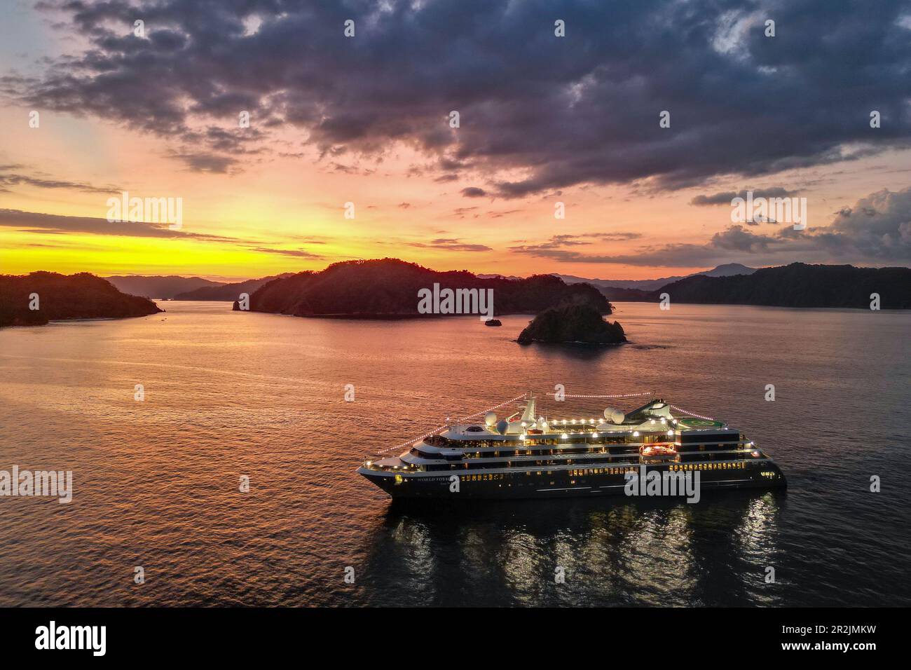 Luftaufnahme vom Expeditionsschiff World Voyager (Nicko Cruises) bei Sonnenuntergang mit Inseln und Küste dahinter, Isla Tortuga, Puntarenas, Costa Ric Stockfoto