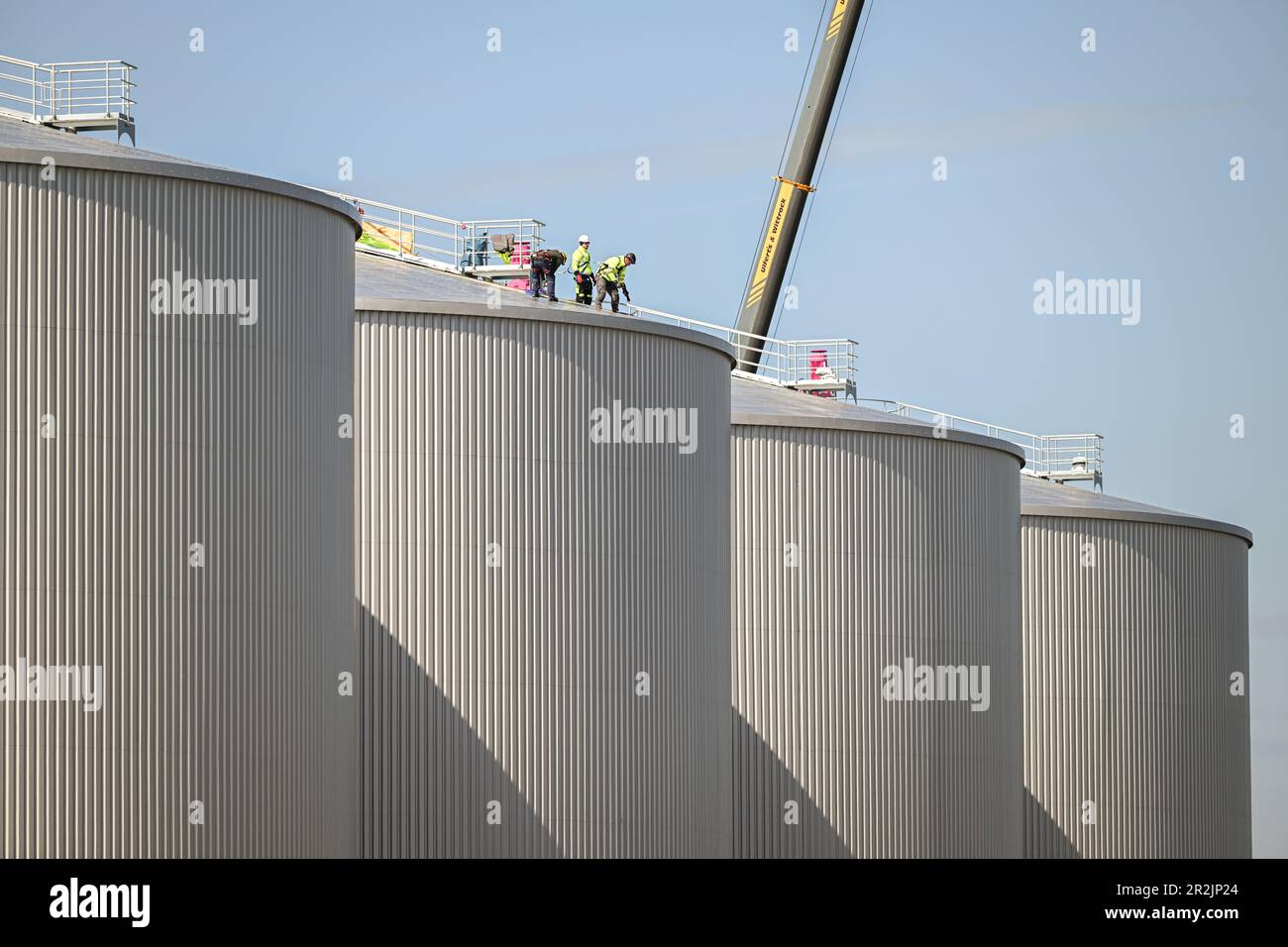 Friesoythe, Deutschland. 08. Mai 2023. Arbeiter stehen während des Baus einer riesigen Biogasanlage auf einem Container. Eine der größten Biogasanlagen in Europa wird derzeit auf einer Fläche von mehr als 13 Hektar in einem Industriegebiet in der Nähe der Kleinstadt Friesoythe bei Cloppenburg gebaut. (An dpa „Biomethan-Anlage im XXL-Format liefert Brennstoff aus Gülle und Gülle“) Kredit: Mohssen Assanimoghaddam/dpa/Alamy Live News Stockfoto
