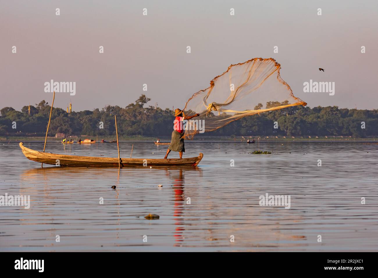 Ein Fischer wirft ein Netz auf den Taungthaman Lake in der Nähe von Mandalay in Myanmar Stockfoto