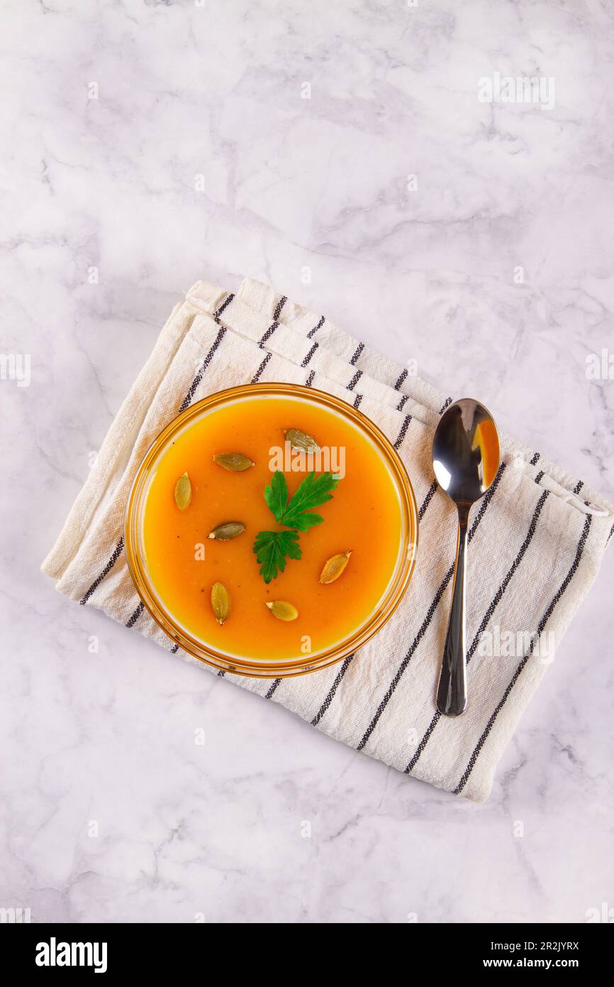 Cremige Kürbissuppe mit glatter Textur, serviert auf Marmorhintergrund mit leerem Platz für zusätzliche Elemente. Stockfoto
