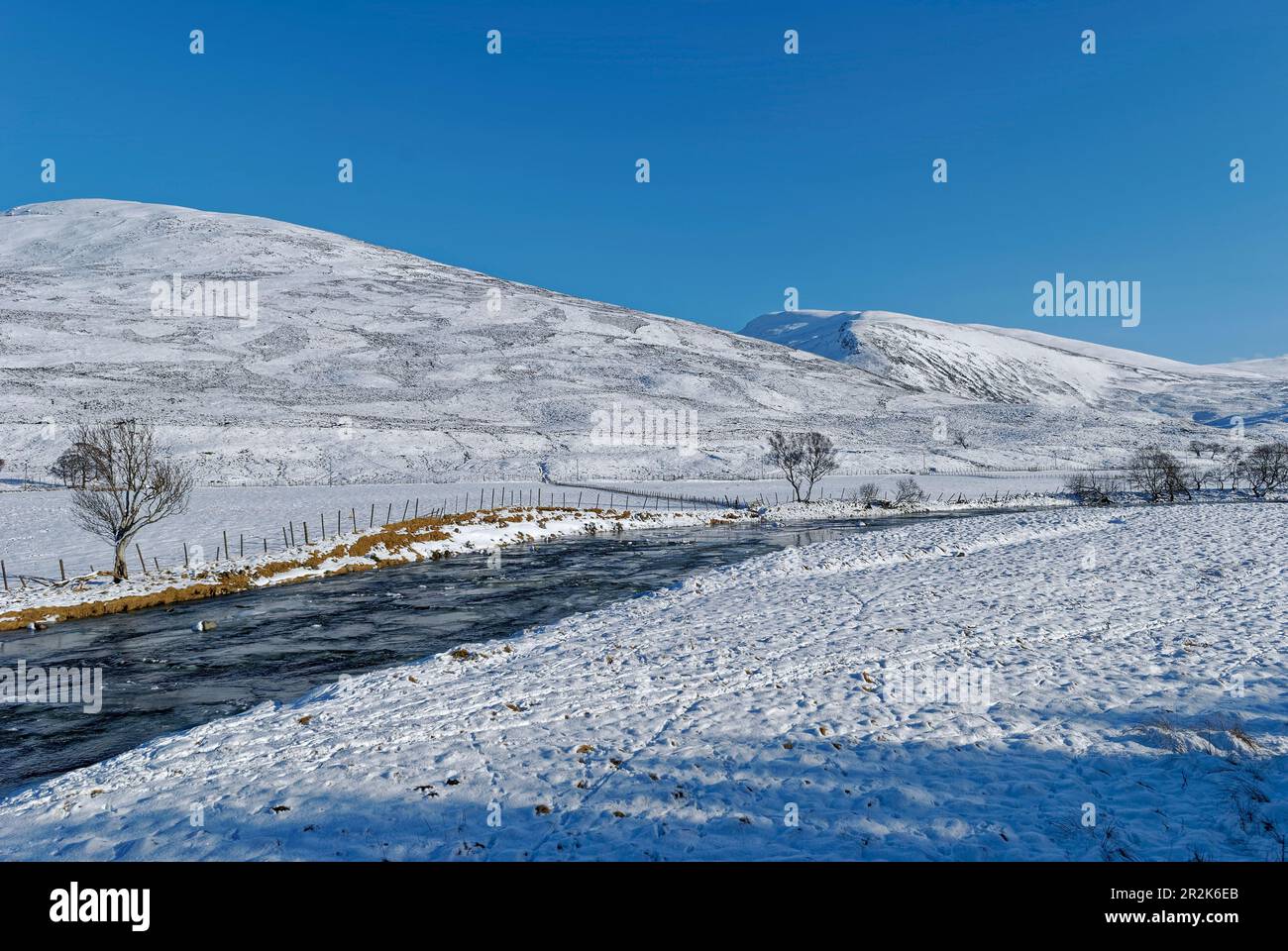 Clunie Wasser fließt das Tal hinunter in Richtung Braemar in Glen Clunie, mit Glenshee in der Ferne an einem Wintertag im Februar. Stockfoto