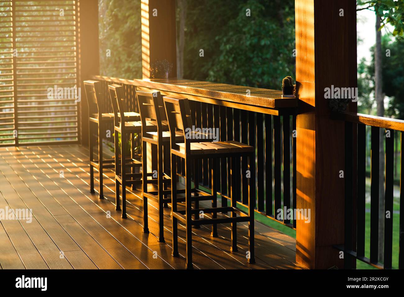 An einem sonnigen Tag stehen auf der Terrasse im Café alte Barhocker aus Holz zur Verfügung. Stockfoto