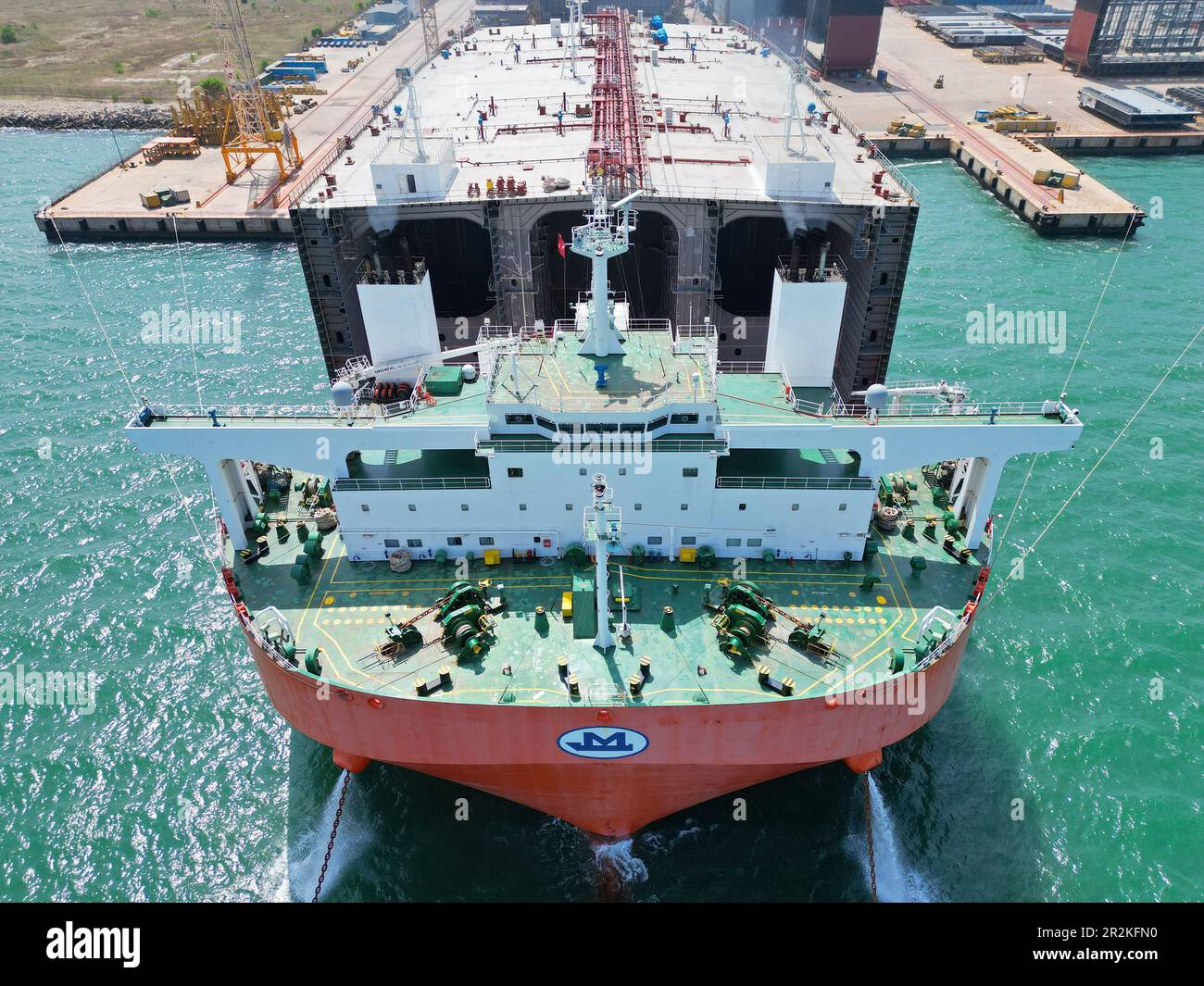 YANTAI, CHINA - 19. MAI 2023 - Ein halb-U-Boot-Schwertransportschiff, das mit Teilen großer Öltanker beladen ist, bereitet sich darauf vor, die Segel eines Schiffes zu setzen Stockfoto