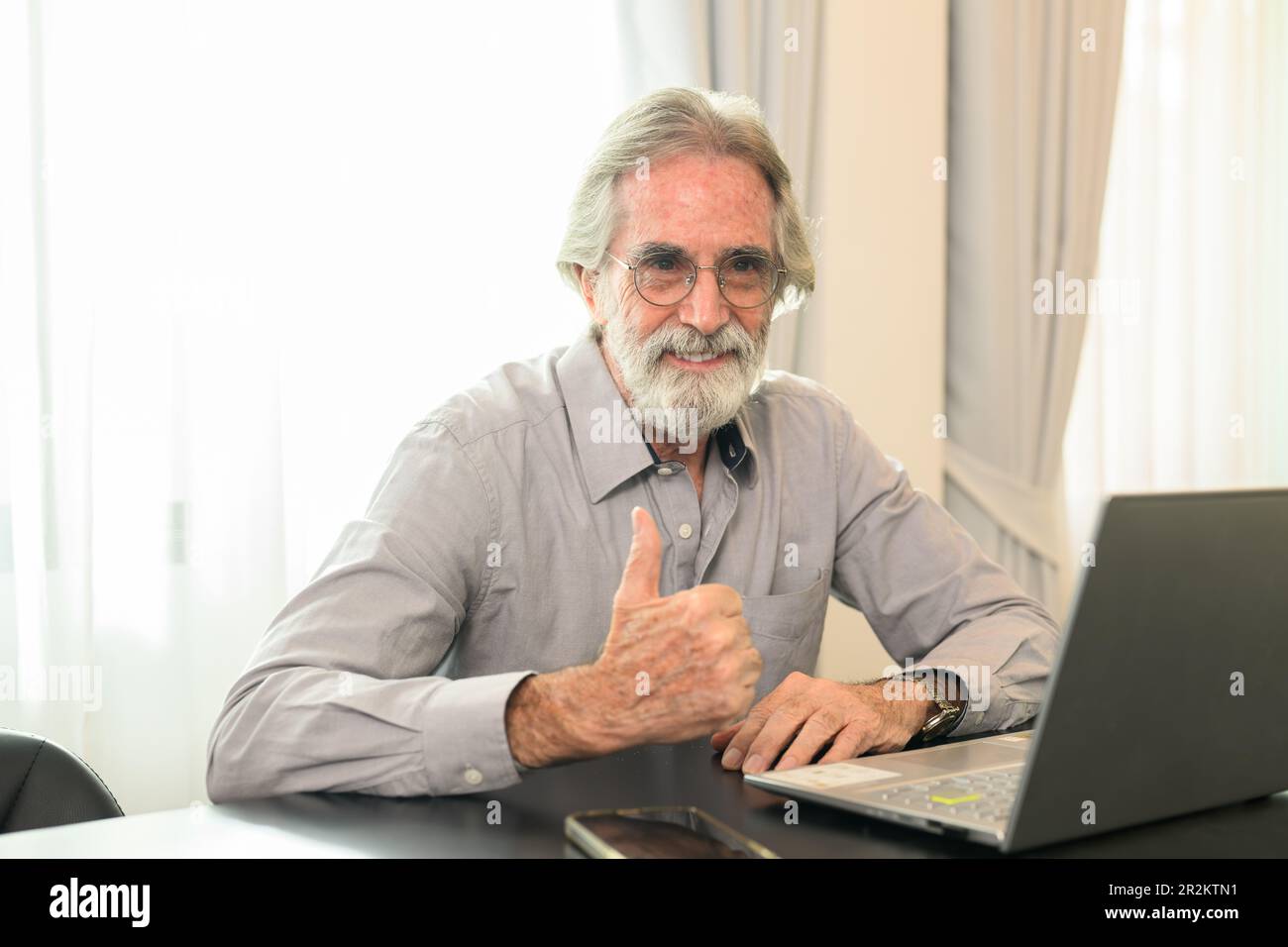 Glücklicher Senior-Mann mit Brille, der sich ein Kameraporträt ansieht Stockfoto