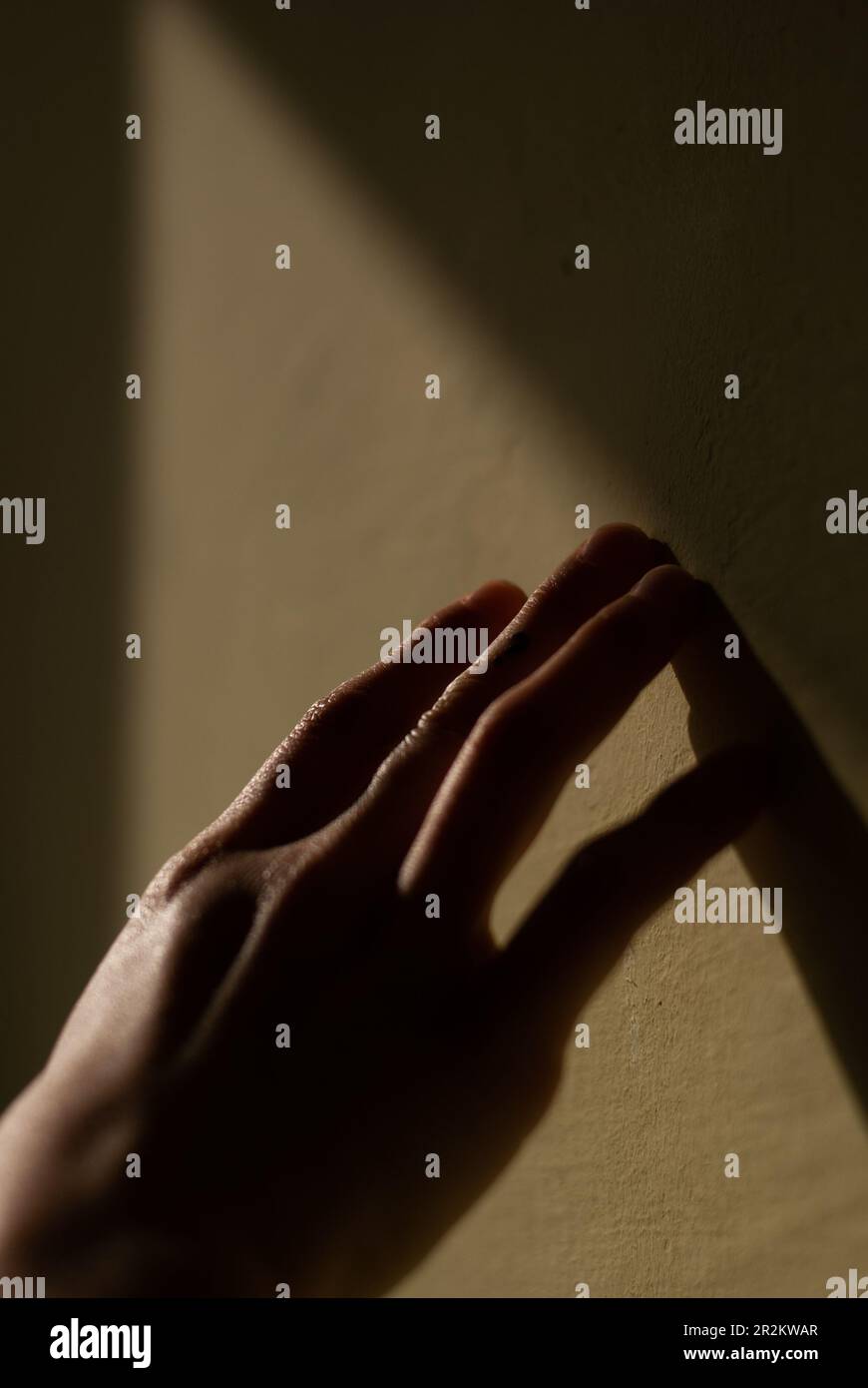Der Blick auf die Hand eines Mädchens berührt eine Wand im Licht der Sonne Stockfoto