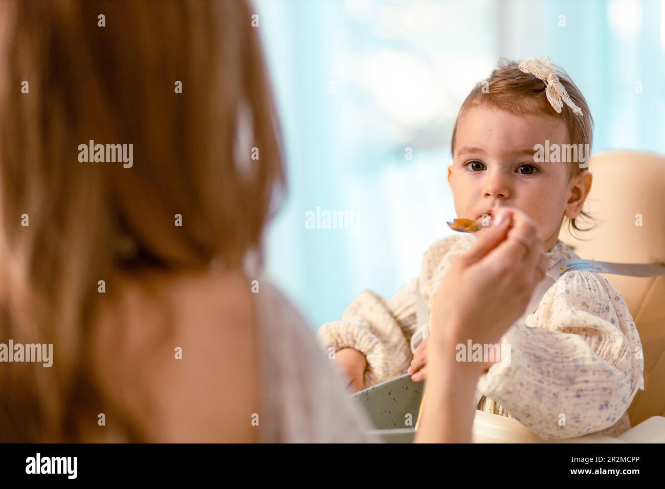 Junge mutter füttert ihre kleine Tochter mit einem Löffel Stockfoto