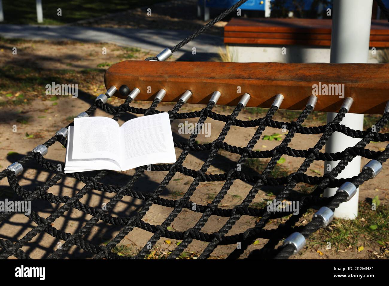 Komfortable NetzHängematte mit offenem Buch im Freien an sonnigen Tagen Stockfoto