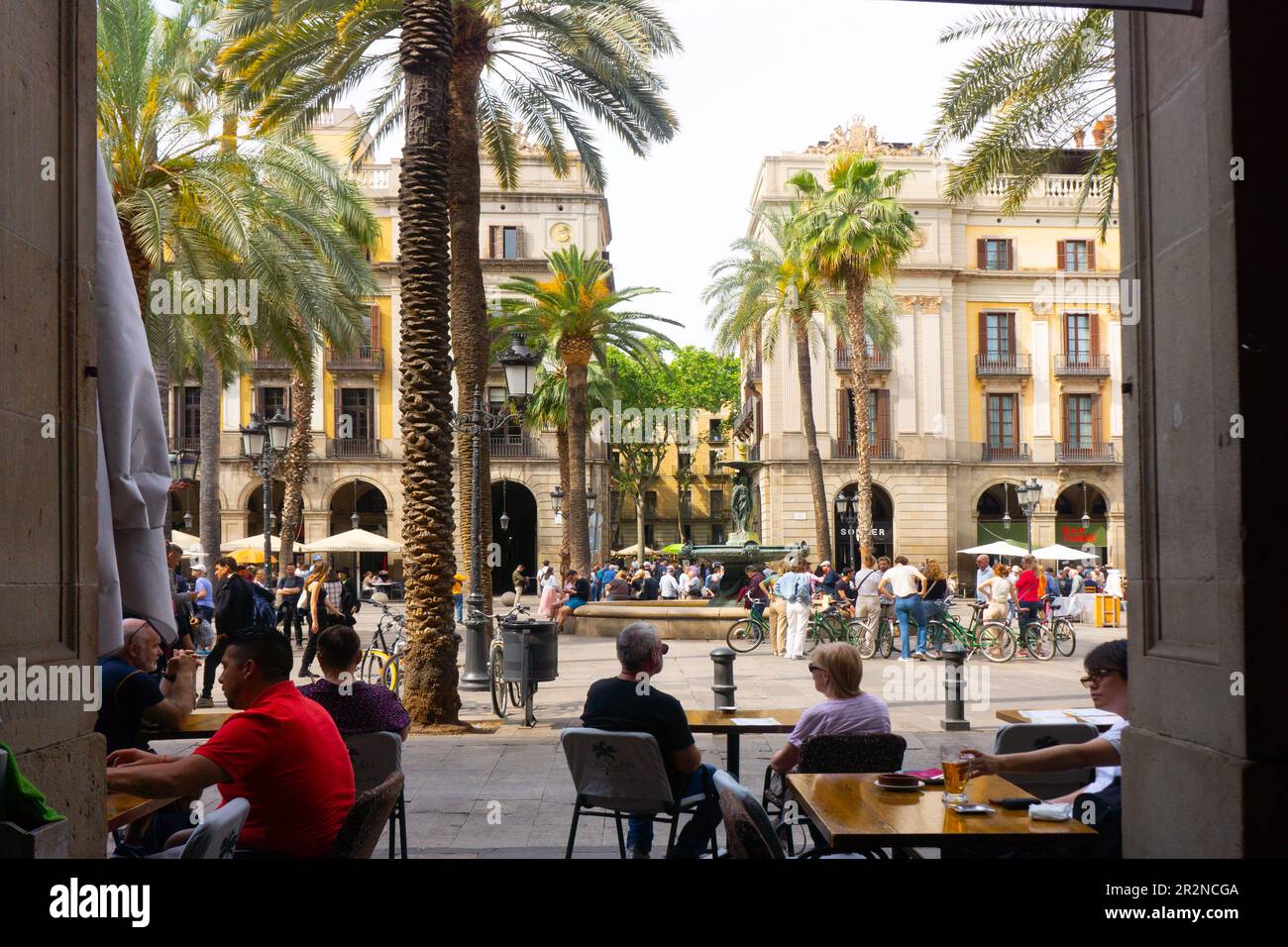 Restaurants und Cafés im Freien umgeben den Placa Reial, vor der Rambla, in Barcelona, Spanien. Beliebt bei Straßenmusikern und Touristen. Stockfoto