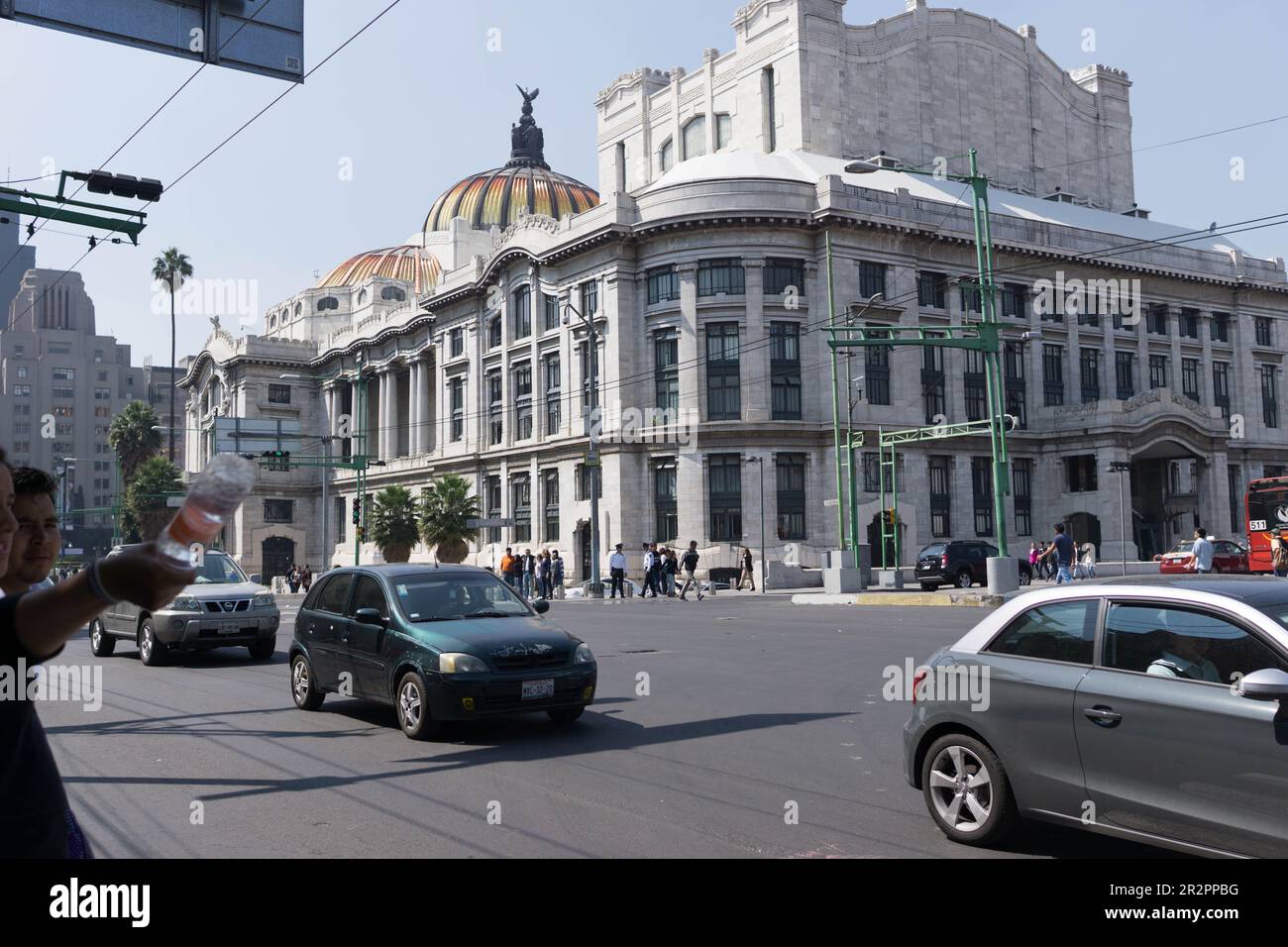 Straßenszene mit Autos und Menschen im historischen Viertel von Mexiko, Mexiko-Stadt, Mexiko, mit dem Palacio de Bellas Artes von der Straßenseite. Stockfoto