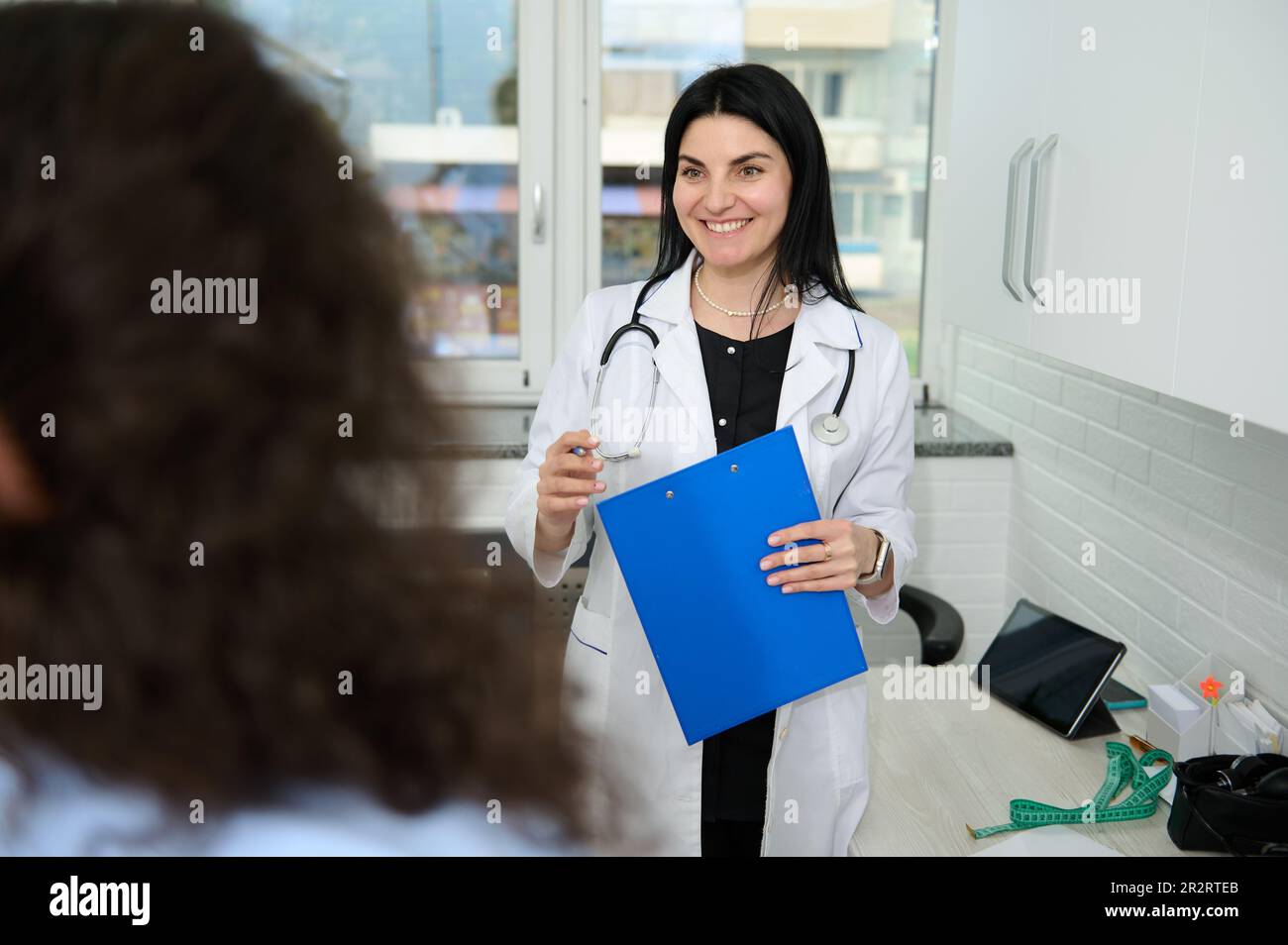 Vertraue der Weißen Frau an, der weiblichen Ärztin Allgemeinmedizin in weißem medizinischen Kleid, lächelt breit, begrüßt ihre Patientin bei der Verabredung Stockfoto Vertraue der Weißen Frau an, der weiblichen Ärztin Allgemeinmedizin in weißem medizinischen Kleid, lächelt breit, begrüßt ihre Patientin bei der Verabredung Stockfoto