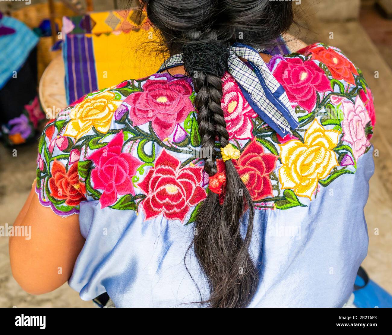 Traditioneller Look einer einheimischen Mexikanerin mit geflochtenem Haar und blauem Hemd mit bunten Blumen Stockfoto