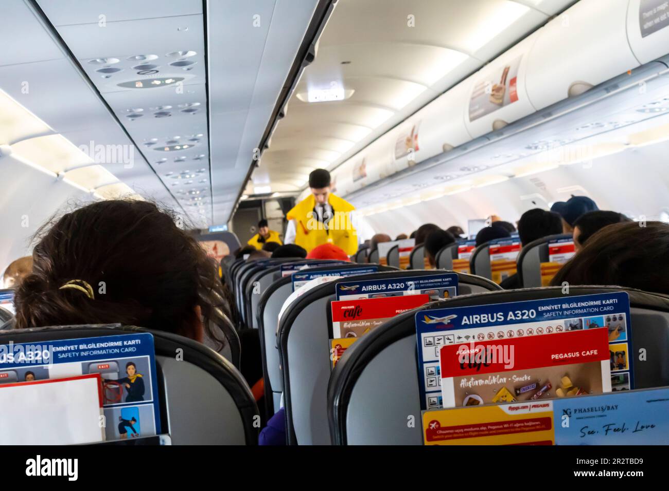 Eine Flugbegleiterin, die unscharf ist und Passagieren in einer Boeing 737, die von Pegasus Airlines betrieben wird, eine Rettungsweste vorführt Stockfoto