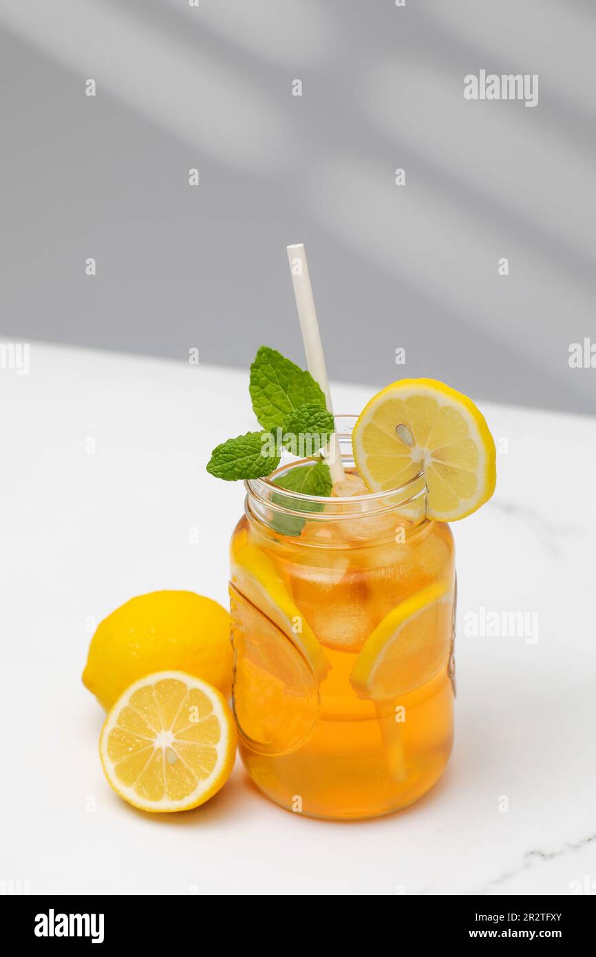 Ein Glas kalten Tee, Eiswürfel, Zitronenscheiben und einen Pfefferminzzweig. Kühle Sommergetränke. Stockfoto