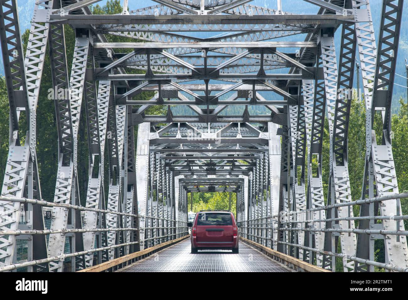 Aus Sicht des Fahrers auf einer Stahlkastenbrücke über den Fluss in Kanada mit einem roten Van, der vorne auf dem Brückendeck aus Stahlgitter fährt Stockfoto