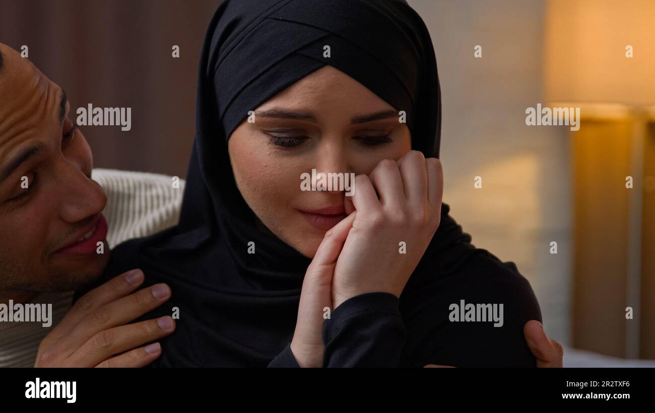 Ein afroamerikanischer Mann interessiert sich für traurig beleidigte, weinende arabische muslimische Frau vielfältiges, multirassisches Paar sitzt drinnen, liebt Ehemann, beruhigt Ehefrau kuschelt Stockfoto