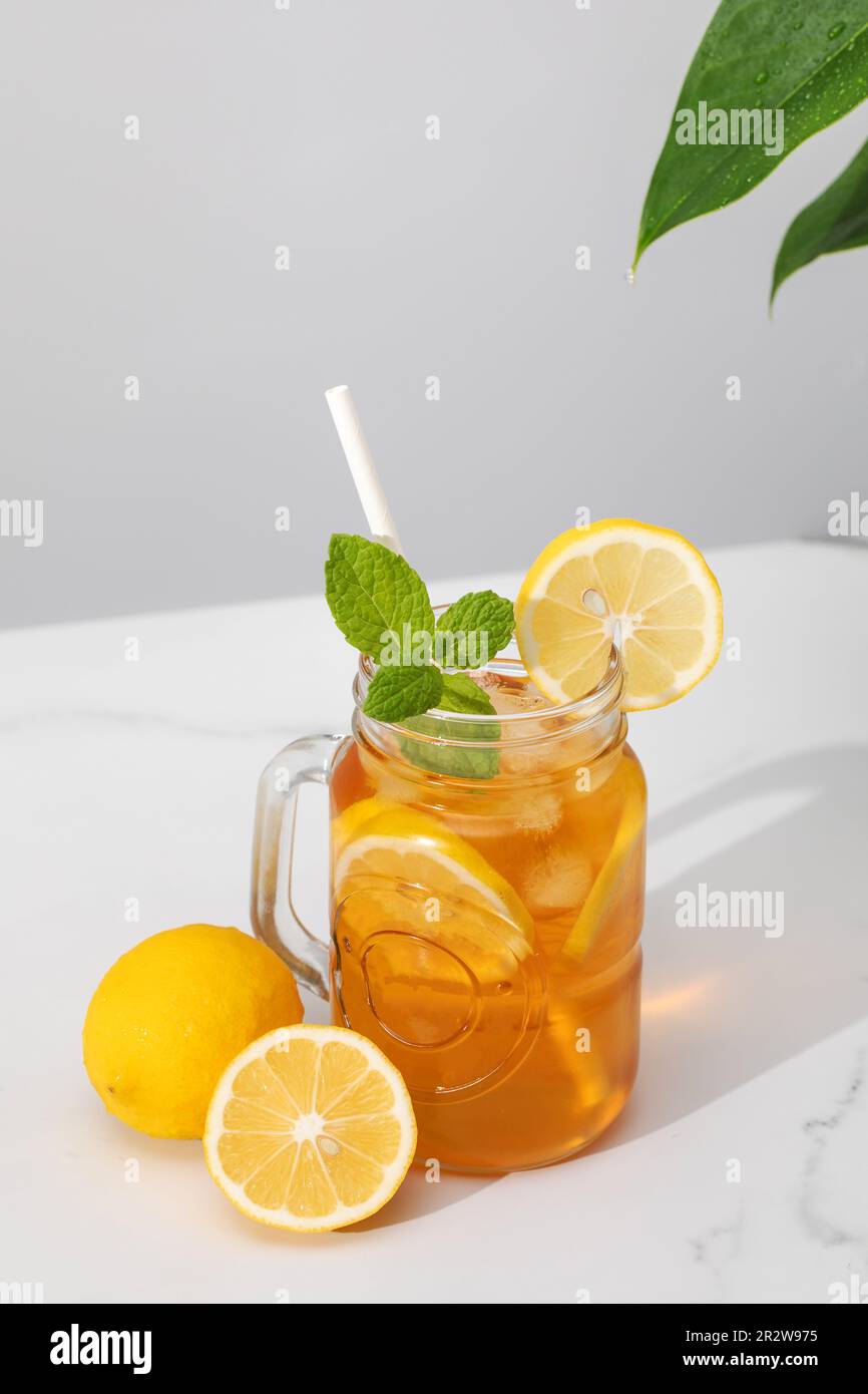 Ein Glas kalten Tee, Eiswürfel, Zitronenscheiben und einen Pfefferminzzweig. Kühle Sommergetränke. Stockfoto