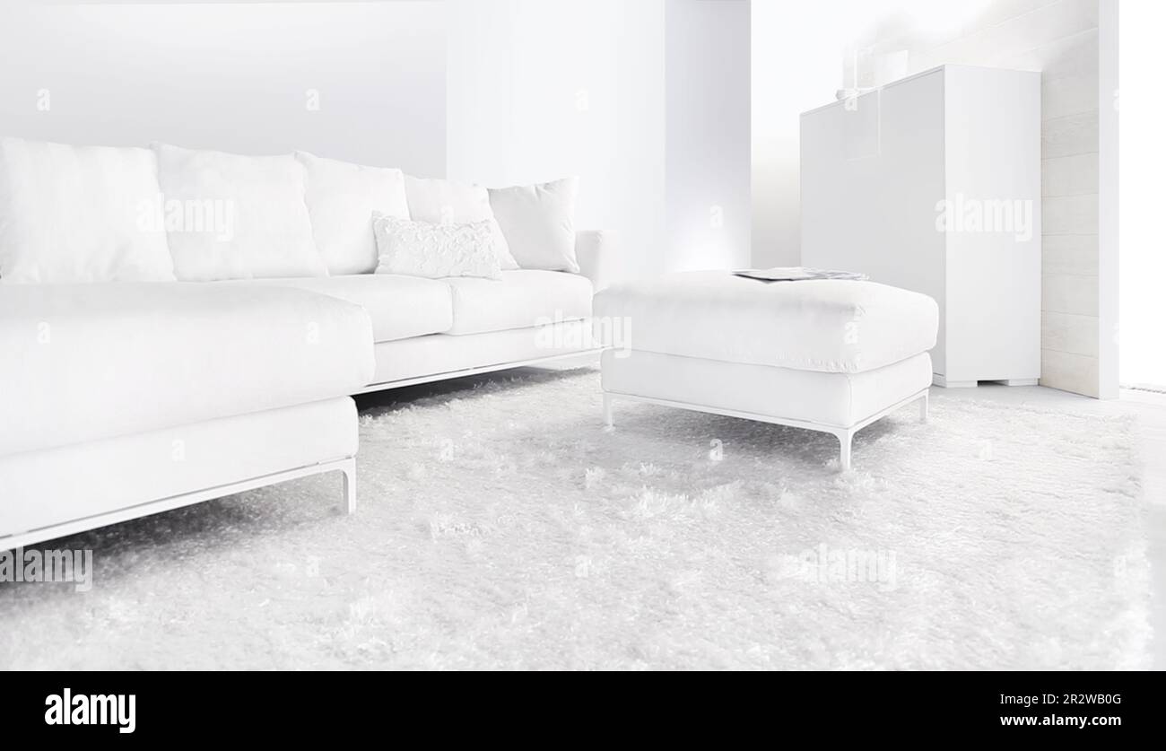 Weiße Couch im hellen, modernen Wohnzimmer. Ecksofa mit weißen Kissen auf weißem Teppich. Stockfoto