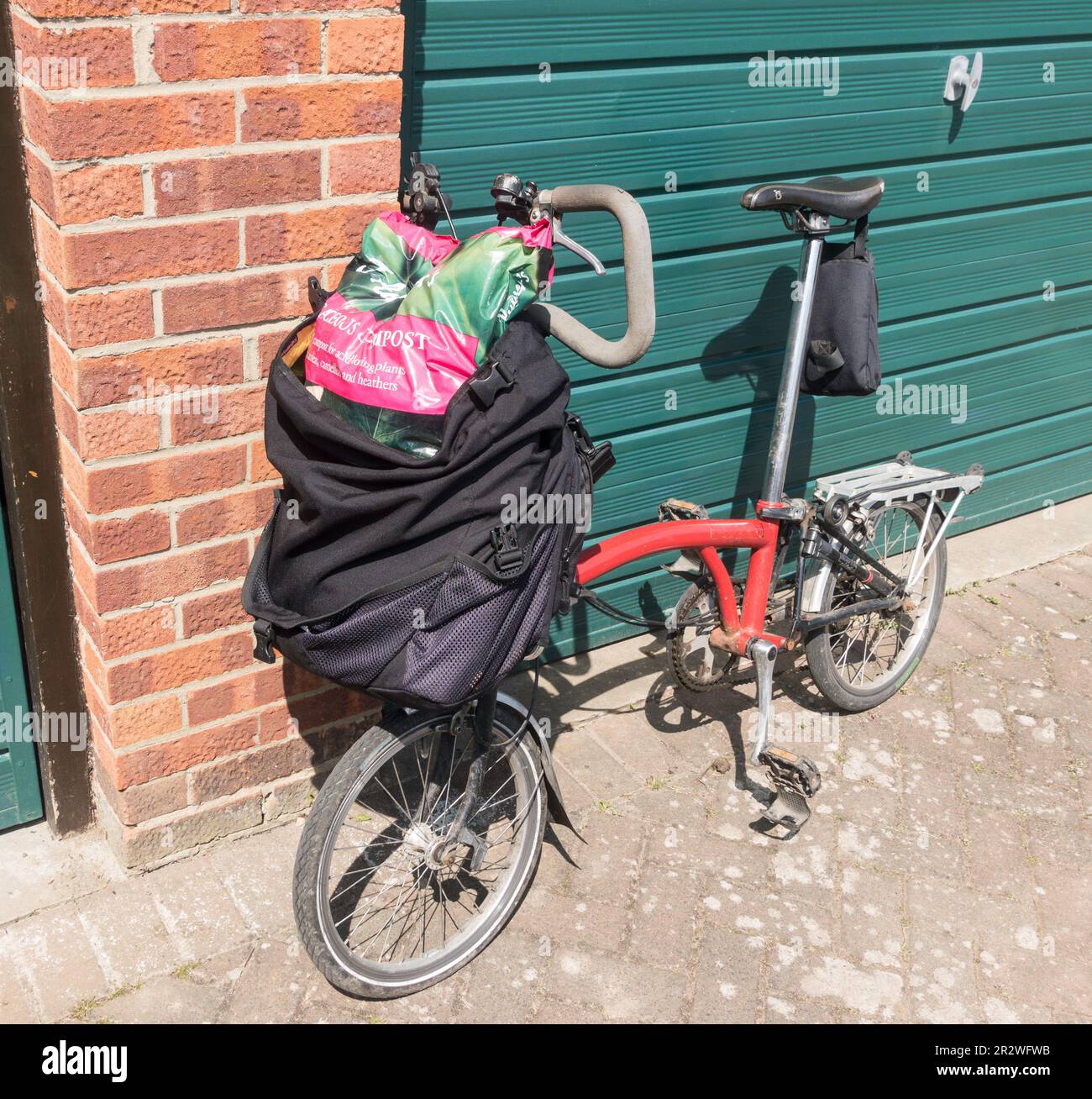 Ein Brompton-Bike mit einer 50L-Tüte Gartenkompost. Stockfoto