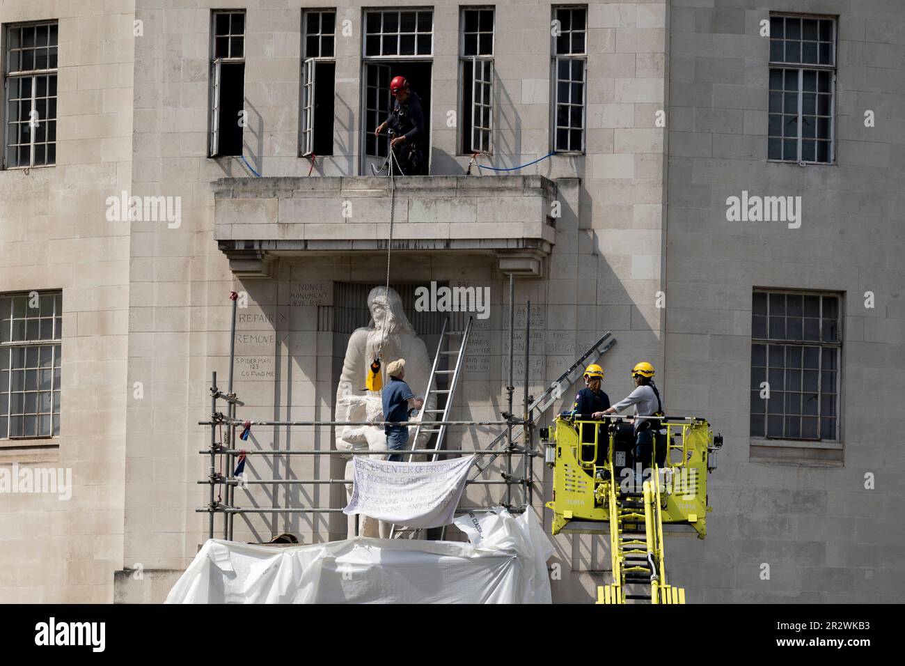 London, Großbritannien. 20. Mai 2023. Zwei Unterhändler der Met Police verhandeln mit dem Demonstranten, während ein anderer Offizier ihn mit Wasser vom Balkon vor dem Broadcasting House versorgen sieht. Ein Mann kletterte auf das Scaffolding Broadcasting House und zerstörte Eric Gills Prospero und Ariel Statue seit 4am Uhr morgens. Vor kurzem wurden Gerüste aufgestellt, die nach den Schäden, die während der Proteste im Januar entstanden sind, repariert werden sollten. (Foto: Hesther Ng/SOPA Images/Sipa USA) Guthaben: SIPA USA/Alamy Live News Stockfoto