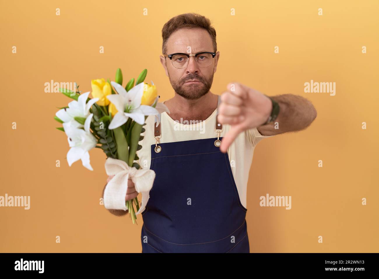 Ein Mann mittleren Alters mit einem Bartfloristenladen, der Blumen hält