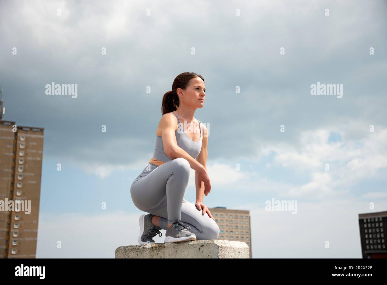 Fit, sportlich Frau kniend, geistig auf Training oder Laufen vorbereitet Stockfoto