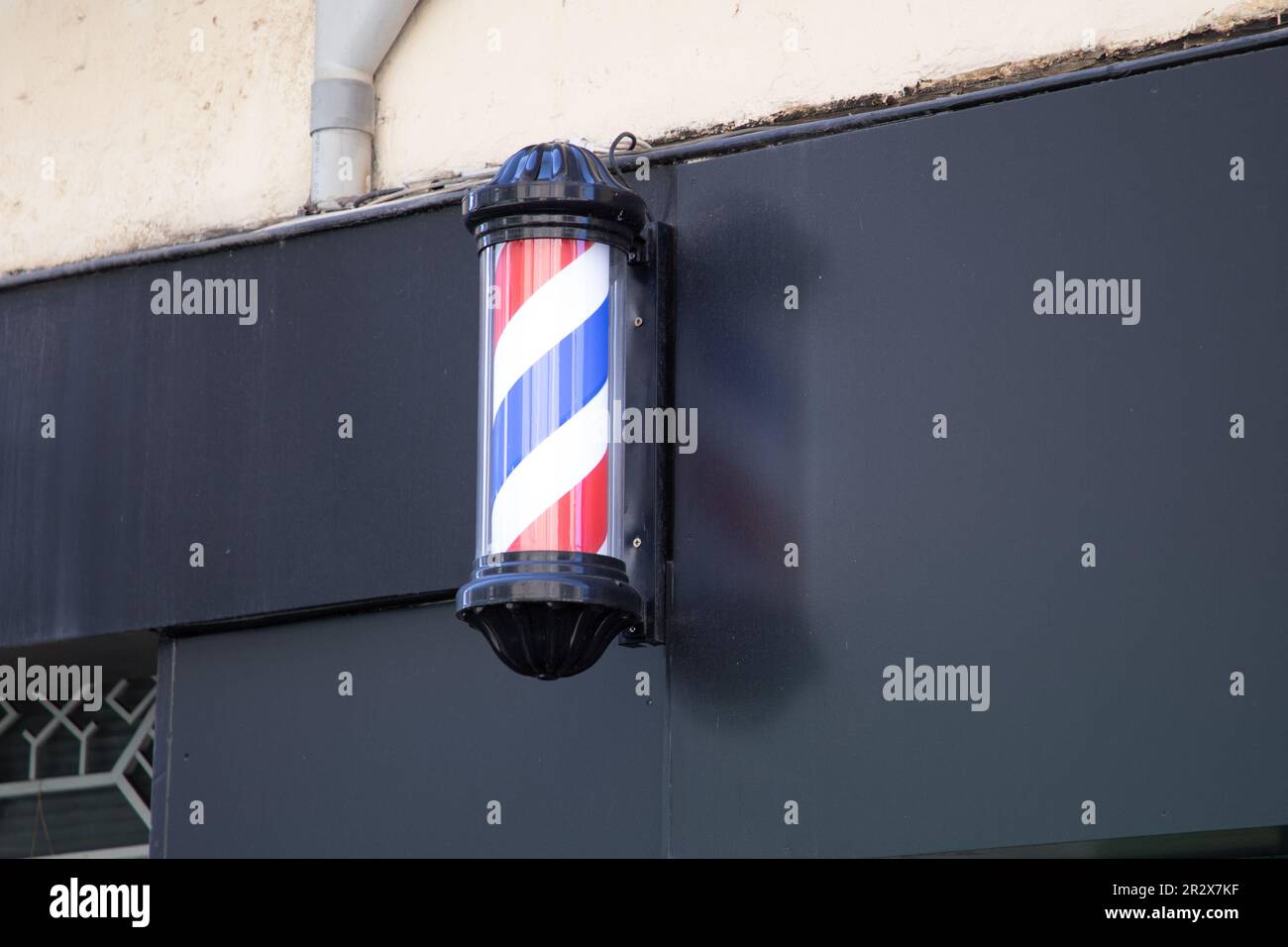 Barberständerladenschild zylindrisches Schild in klassischer Friseurfassade weiß rot-blau Stockfoto