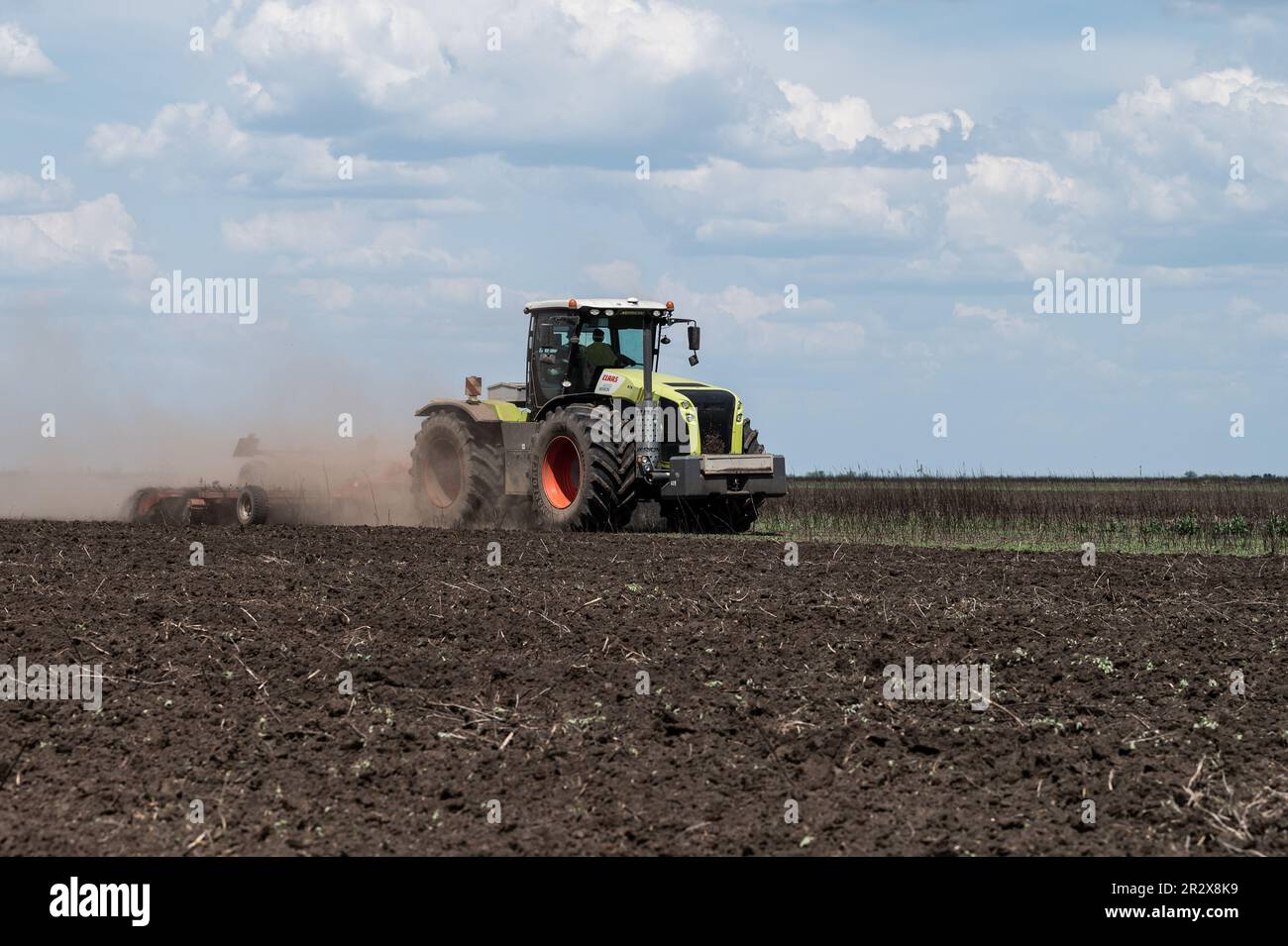 Ein Traktor, der ein Feld pflügt, das kürzlich von Landminen geräumt wurde, die während des Krieges zwischen Russland und der Ukraine auf einem Bauernhof in Velyka Oleksandrivka, Ukraine, zurückgelassen wurden. Stockfoto