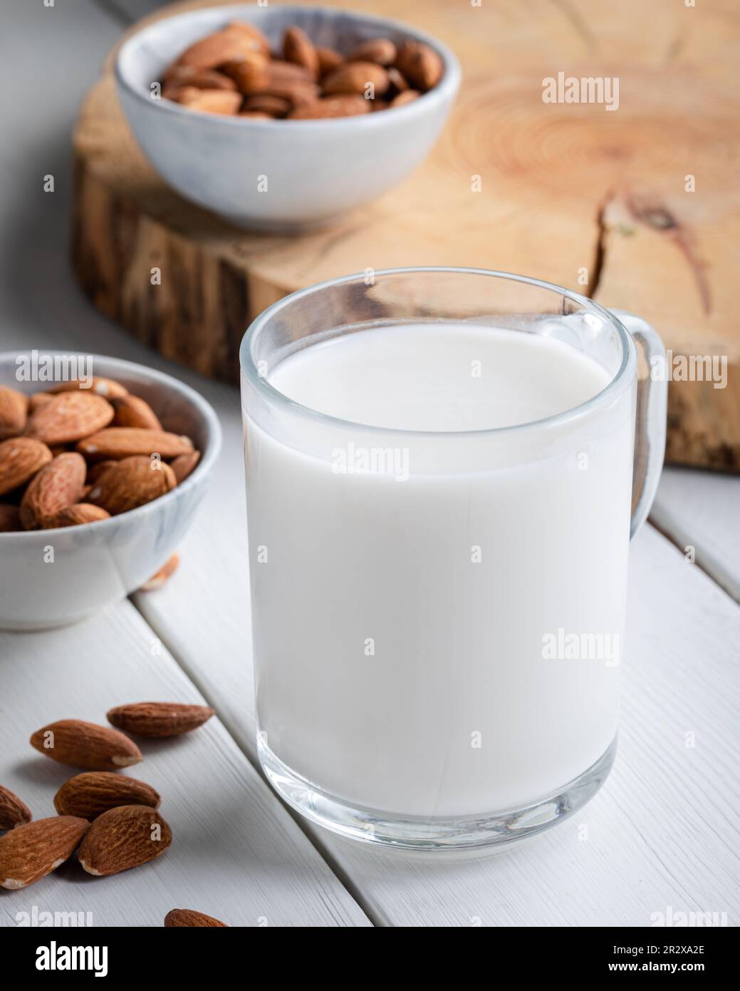 Mandelmilch aus Glas mit Mandeln auf hölzernen Hintergrund. Stockfoto