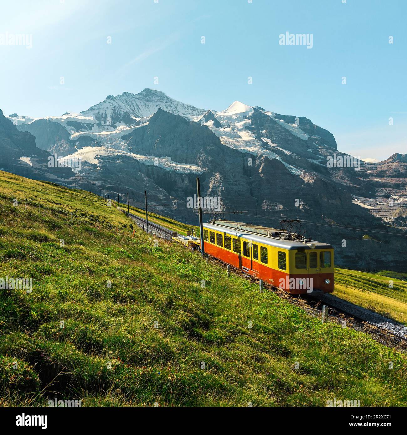 Zahnradbahn mit kleinem roten Touristenzug. Verschneite Jungfrau Berge und roter Passagierzug auf dem Jungfraujoch, kleine Scheidegg, Grinde Stockfoto