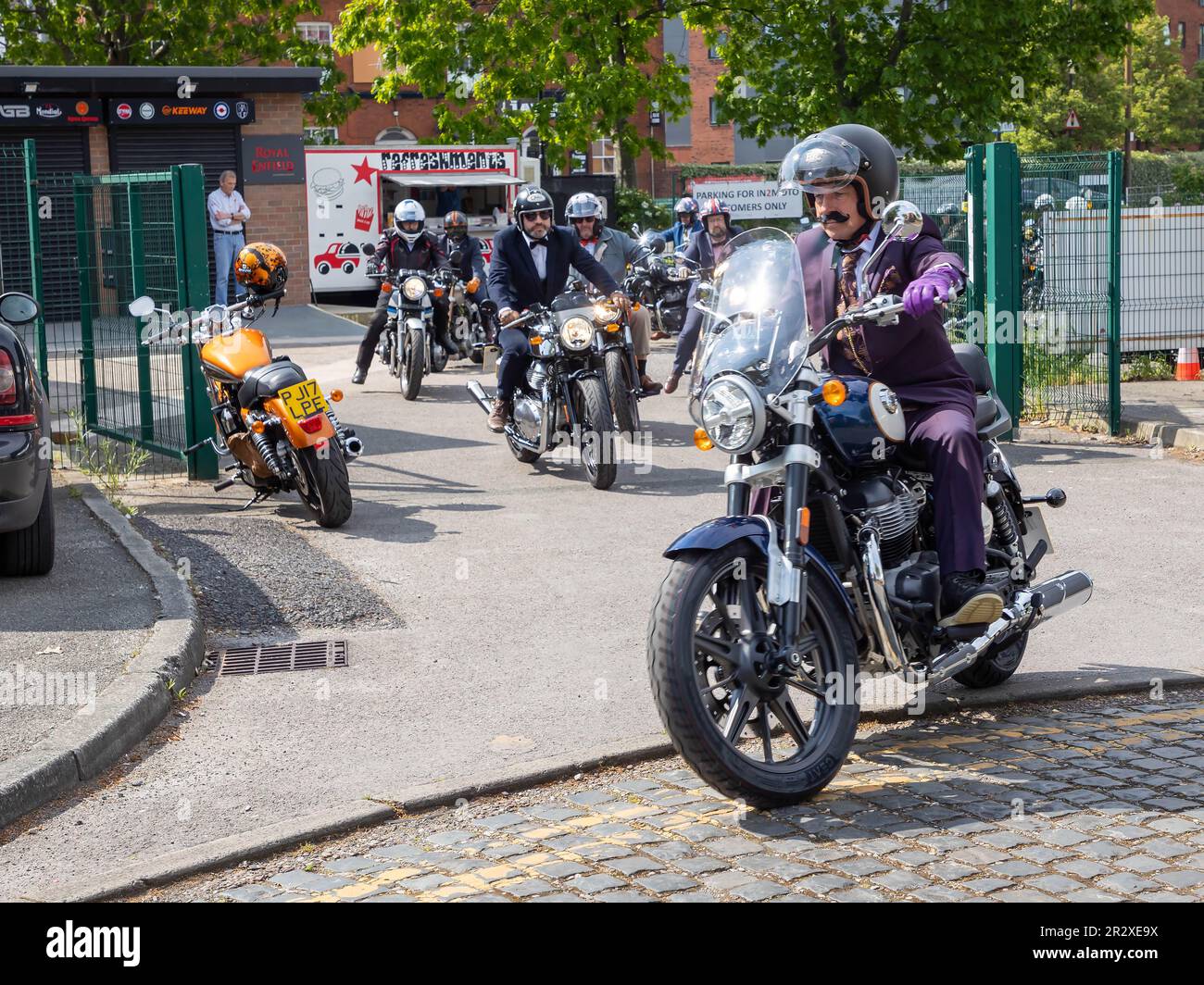 Warrington, Cheshire, Großbritannien. 21. Mai 2023. Großbritannien - die Distinguished Gentleman's Ride (DGR) vereint klassische und klassische Motorradfahrer aus der ganzen Welt, um Mittel und Bewusstsein für die Prostatakrebsforschung und die psychische Gesundheit von Männern zu sammeln. Eine Gruppe von Motorradfahrern startete in Warrington in ihren besten Anzügen und Krawatten, trafen sich bei ihrem Motorradhändler vor Ort und fuhren dann durch das Stadtzentrum, bevor es aus der Stadt und durch eine Kombination aus Dörfern und Städten ging. Sie landeten im Besucherzentrum der Jodrell Bank. Kredit: John Hopkins/Alamy Live News Stockfoto