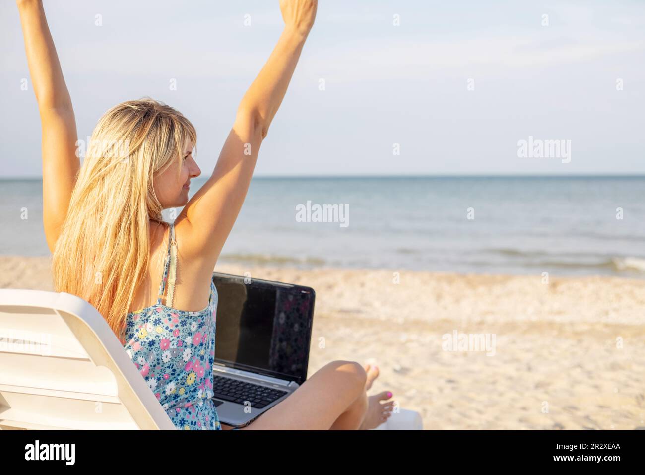 Rückansicht einer jungen blonden Frau, weibliche Freiberuflerin, die an einem Laptop arbeitet Stockfoto