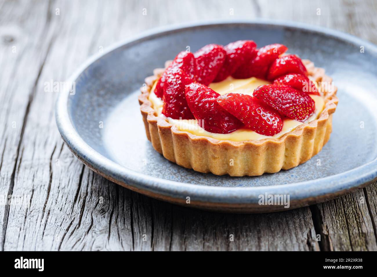 Erdbeertörtchen, französisches Dessert auf einem rustikalen Holztisch in heller Atmosphäre Stockfoto